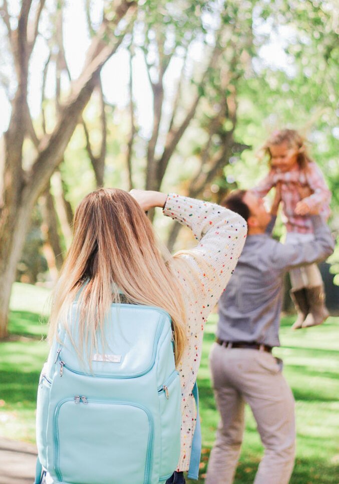  A candid shot of photographer Jacquie Erickson snapping a picture of a father, swinging his young daughter. Client questionnaire Momtog course streamline workflow small business helpers #planoly #dubsado #pixiset #tailwind #theunburdenstudio 