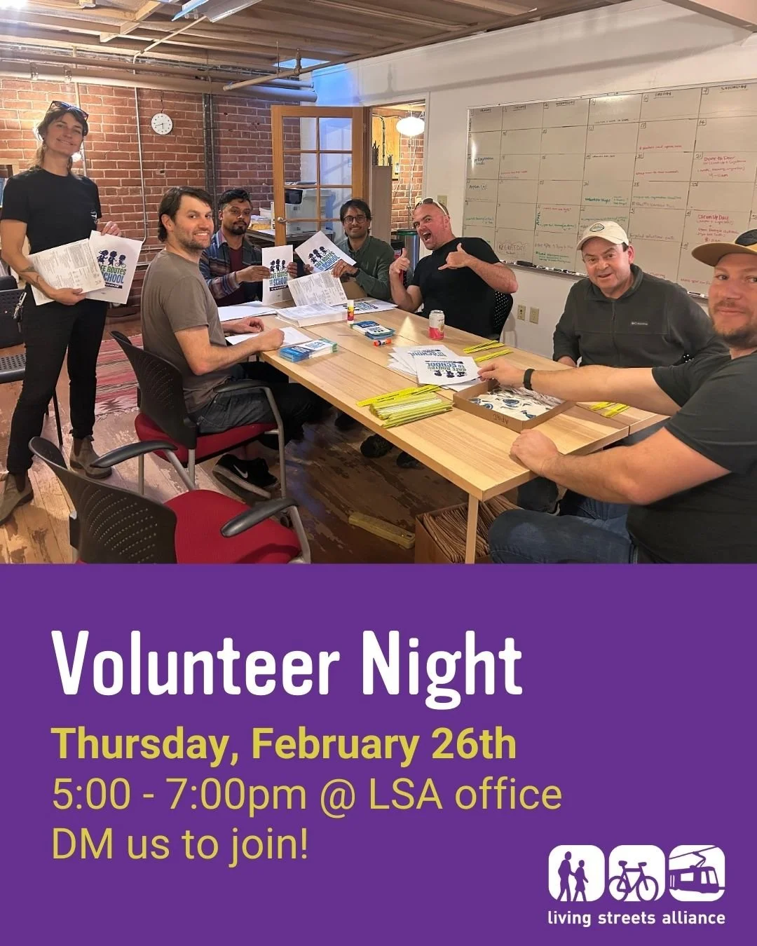 A photo of 7 people around an office table smiling and making goofy faces as they pack educational materials into school baggies. The text reads: Volunteer Night. Thursday, February 26th 5:00 - 7:00 p.m. at the LSA office.