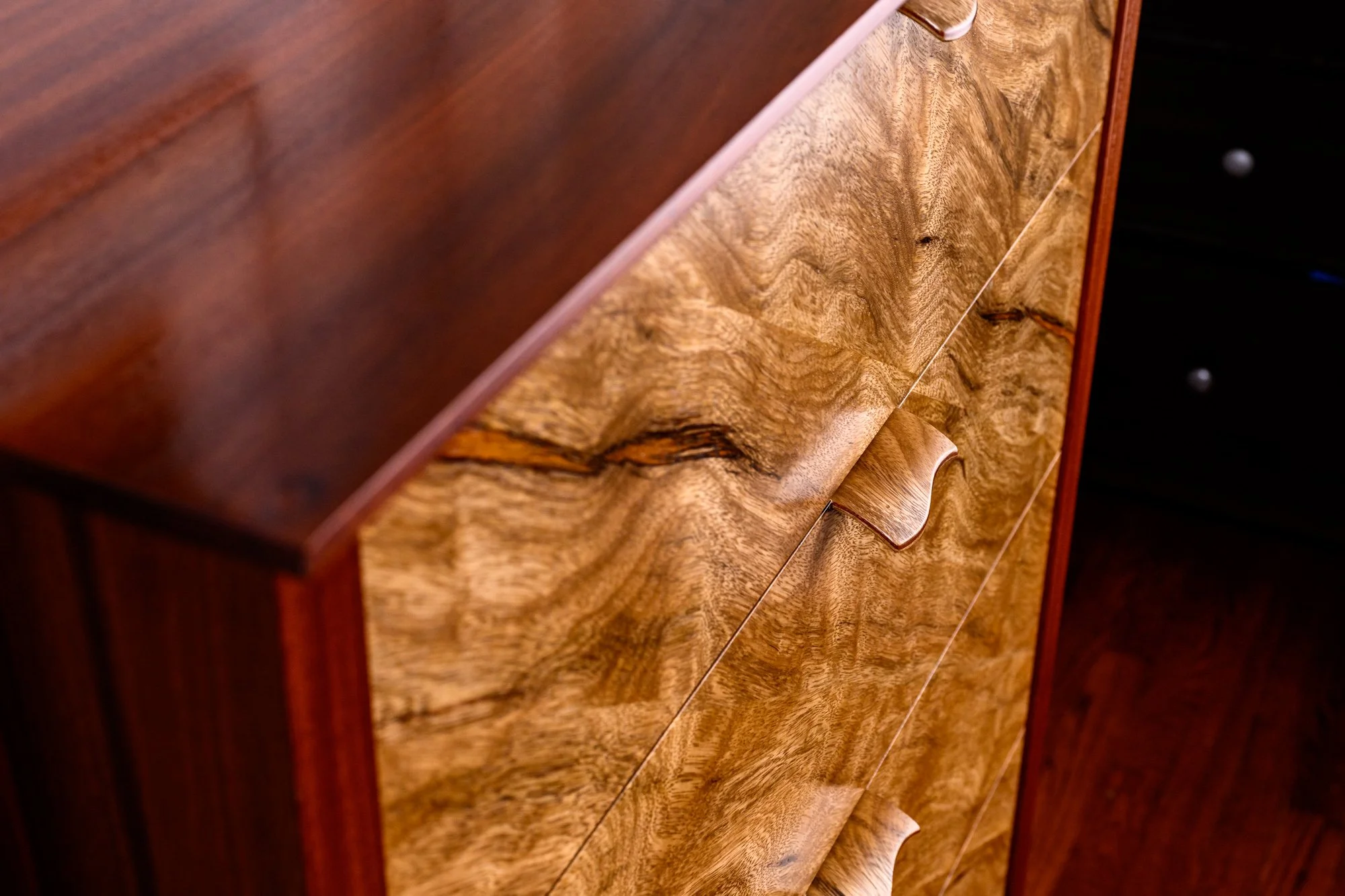 Close-up of a wooden dresser with a natural wood finish and curved drawer handles.