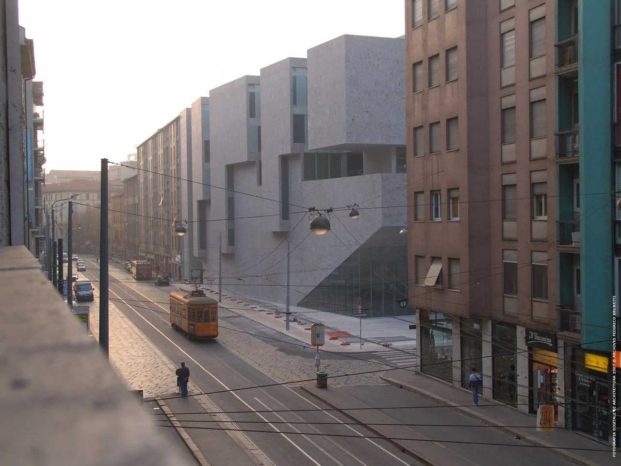 米蘭 Bocconi 大學的灰色混凝土量體建築,街道電車駛過,展現現代都市與建築設計的交融。