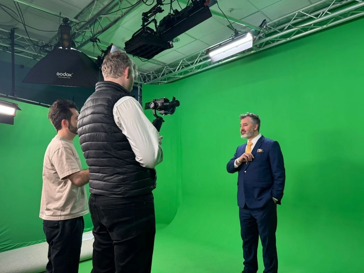 A camera crew filming Anthony in a green-screen studio