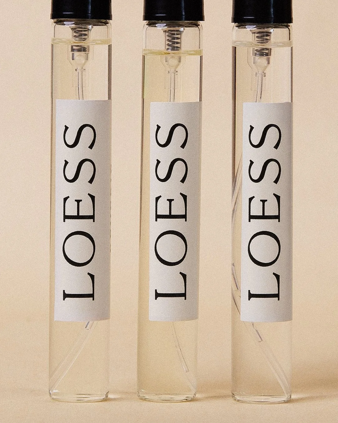 Three test tubes labeled 'LOESES' filled with a clear liquid, standing upright against a beige background.