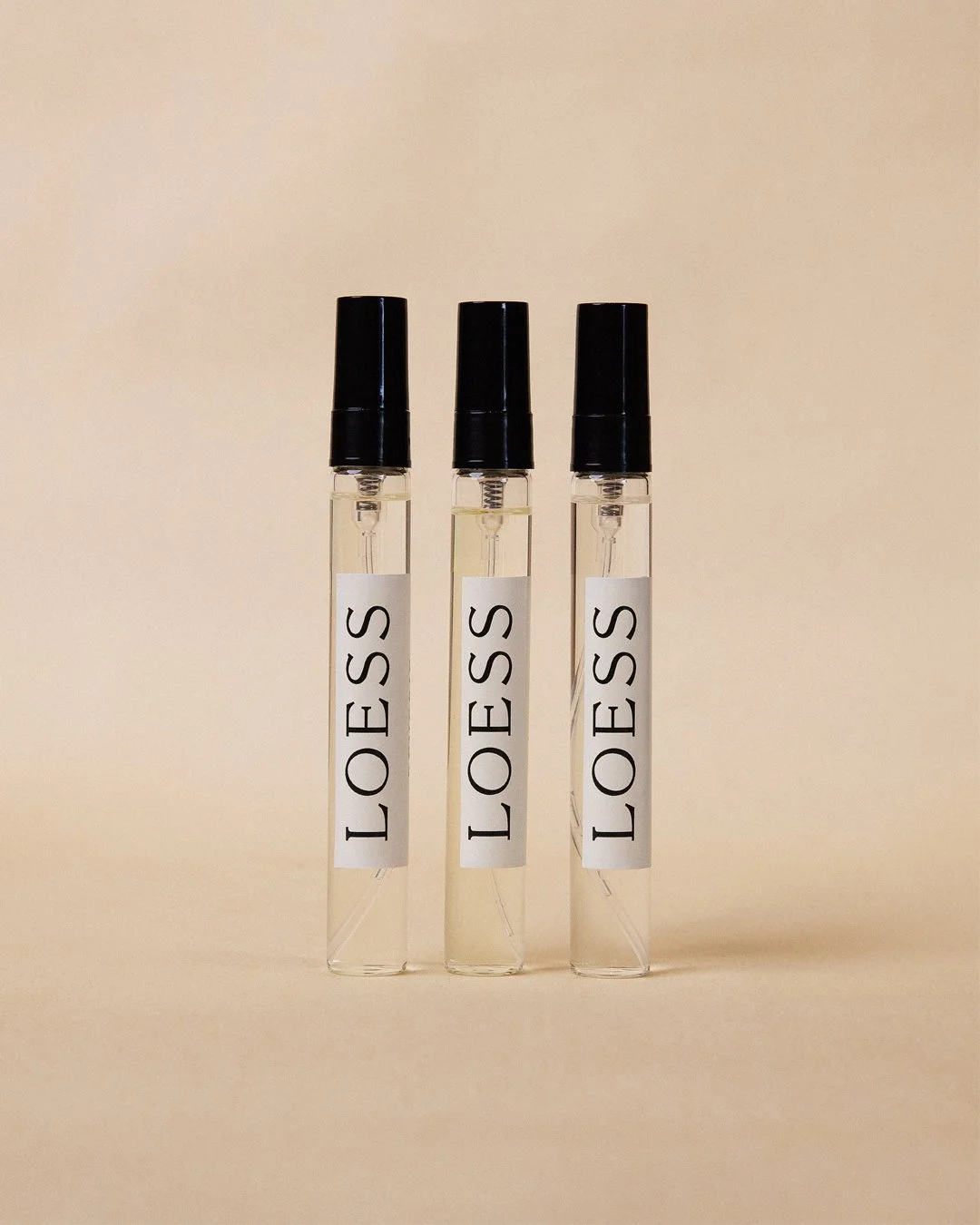 Three test tubes with black caps and white labels reading 'LOESS' on a beige background.