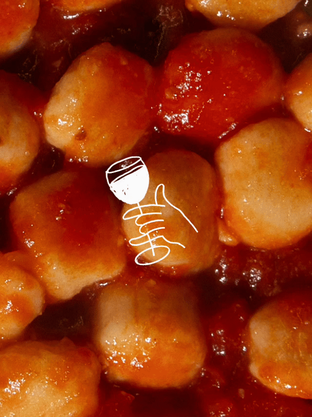 Close-up of cooked meatballs in tomato sauce with a white line drawing of a hand holding a wine glass overlayed.