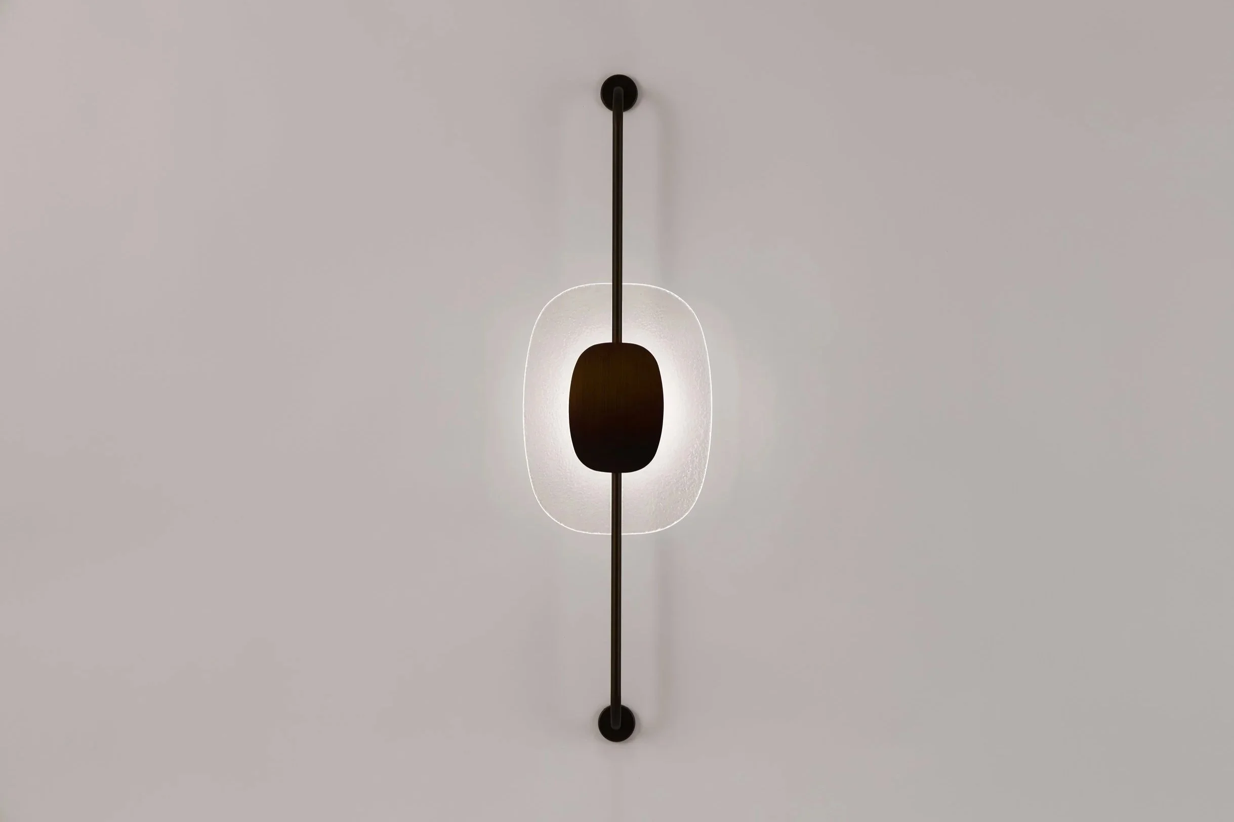 Vertical view of the Drop Light II (Axis) wall sconce by The Touch Studio. Featuring a slender black metallic axis and an amber aquatic-textured glass core. Handcrafted in Italy.
