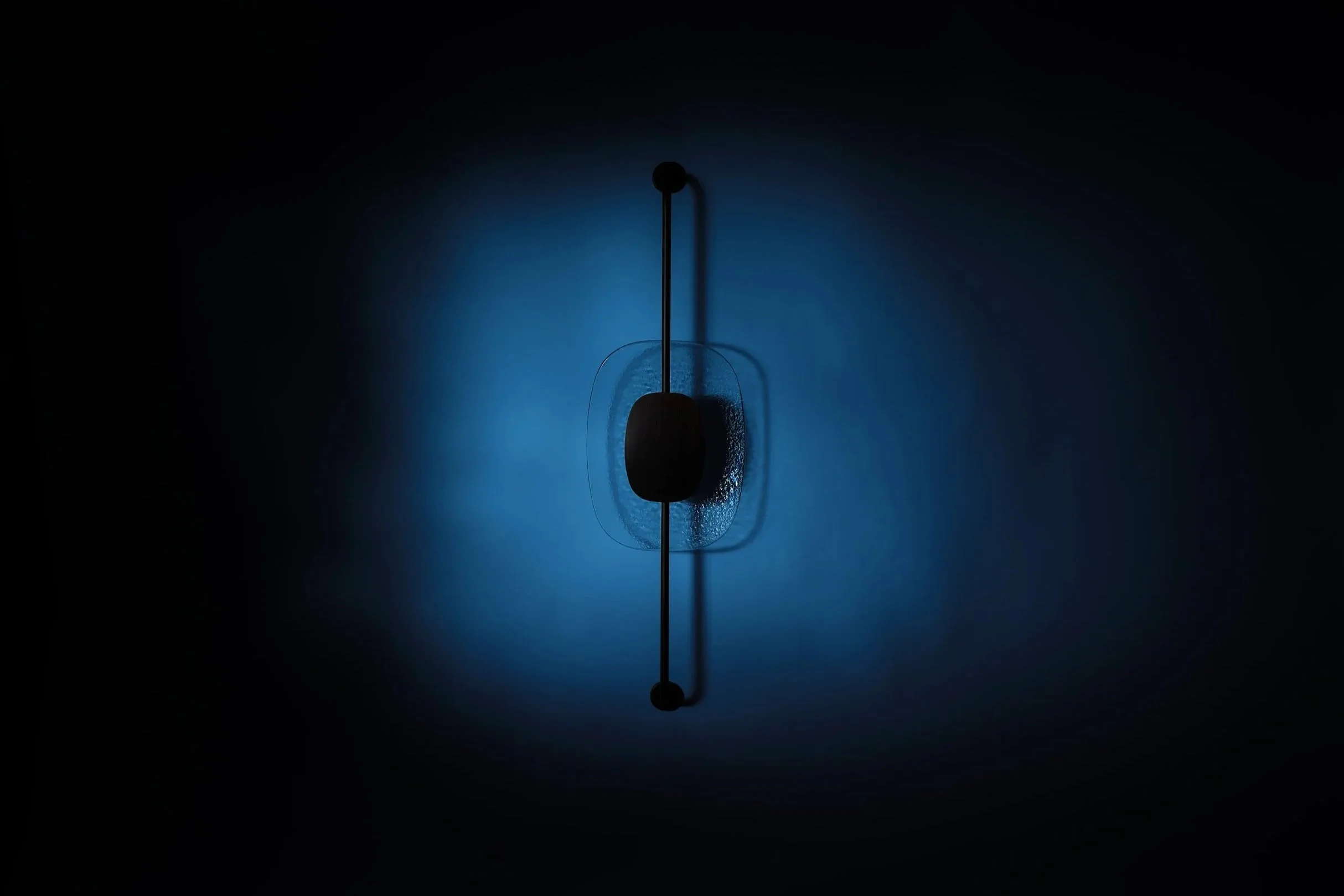 The Drop Light II shown with a cool blue nocturnal glow. The vertical sculptural axis creates a striking contrast against the soft, diffused light, ideal for atmospheric interiors.