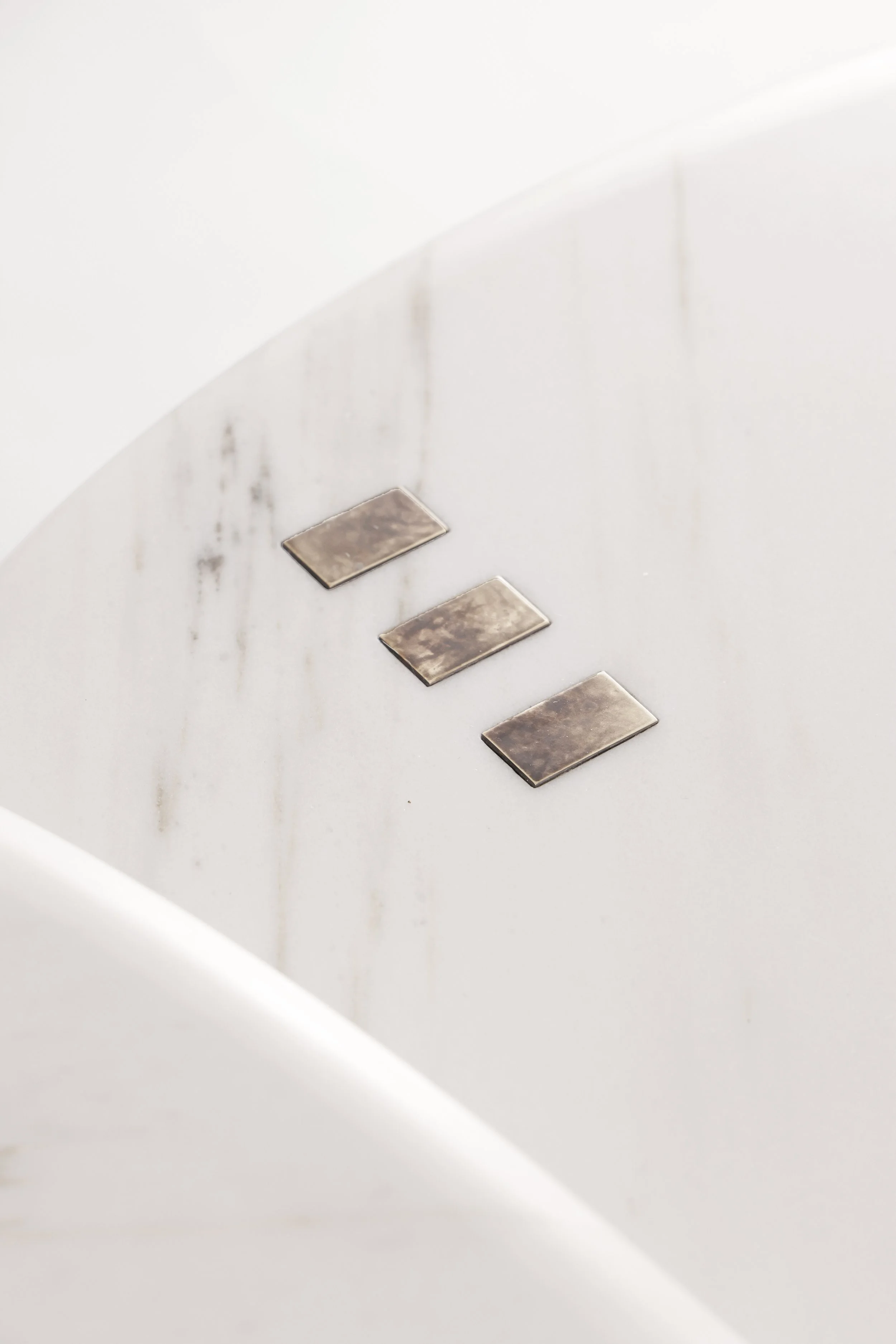Detail of the brass inserts on the Calacatta marble, symbolizing prosperity and the flow of a calm river.