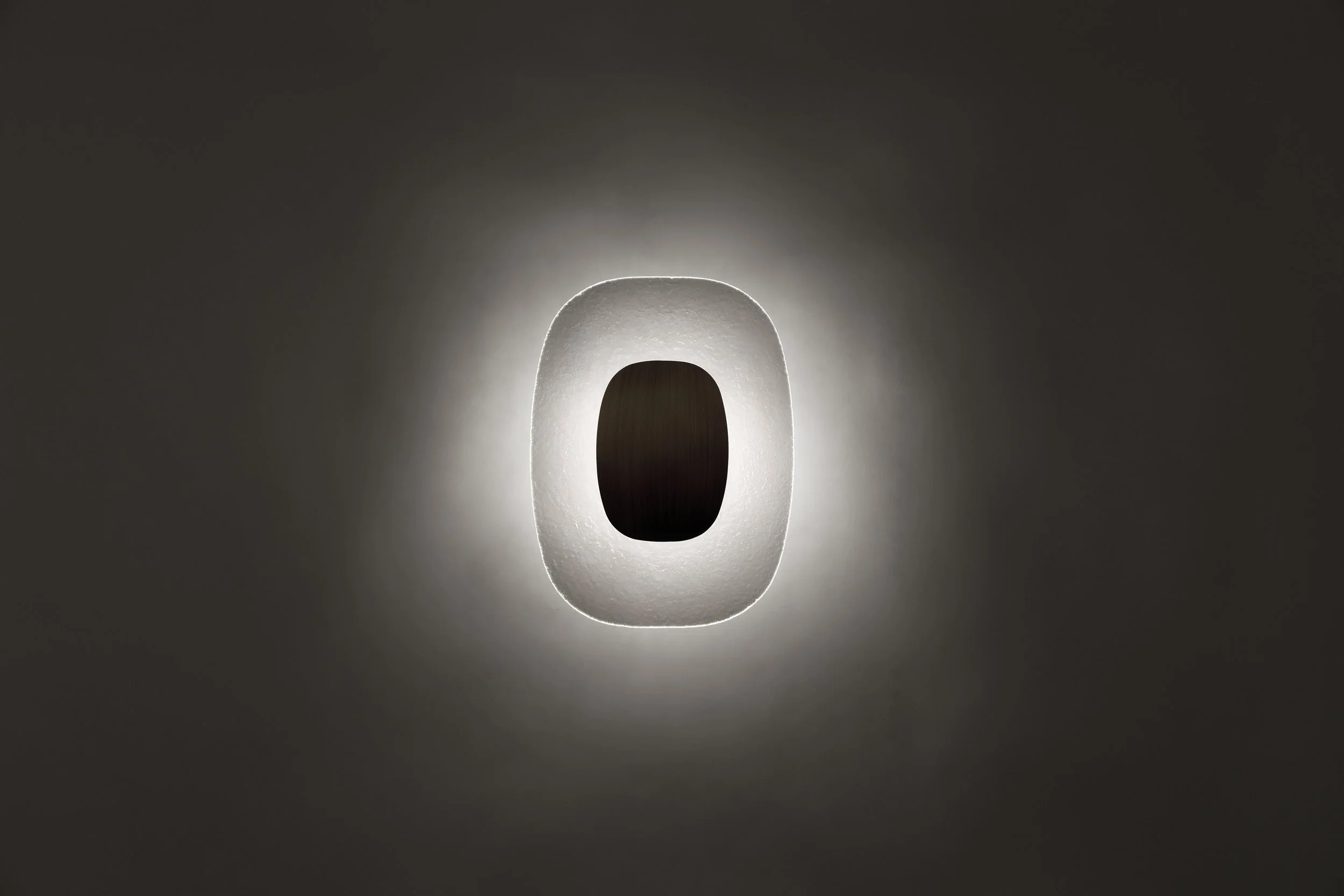 The Drop Light illuminated, highlighting the dialogue between the dark metallic 'pebble' and its ethereal luminous halo.