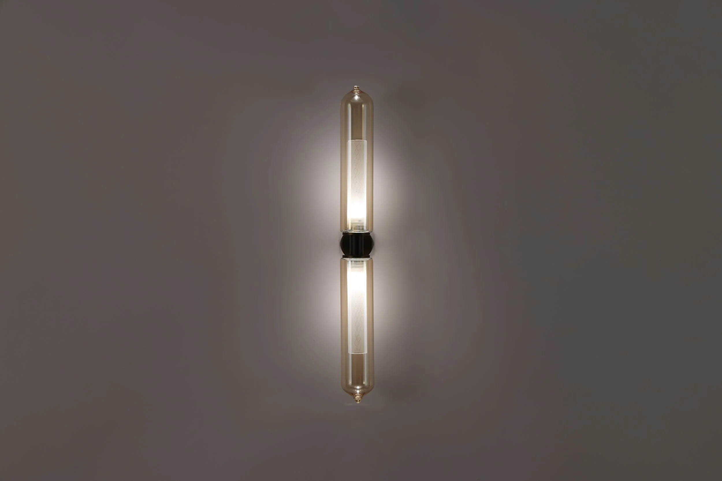 Atmospheric shot of the Bee Applique illuminated against a warm yellow-toned wall, showcasing the intimate and poetic amber glow.