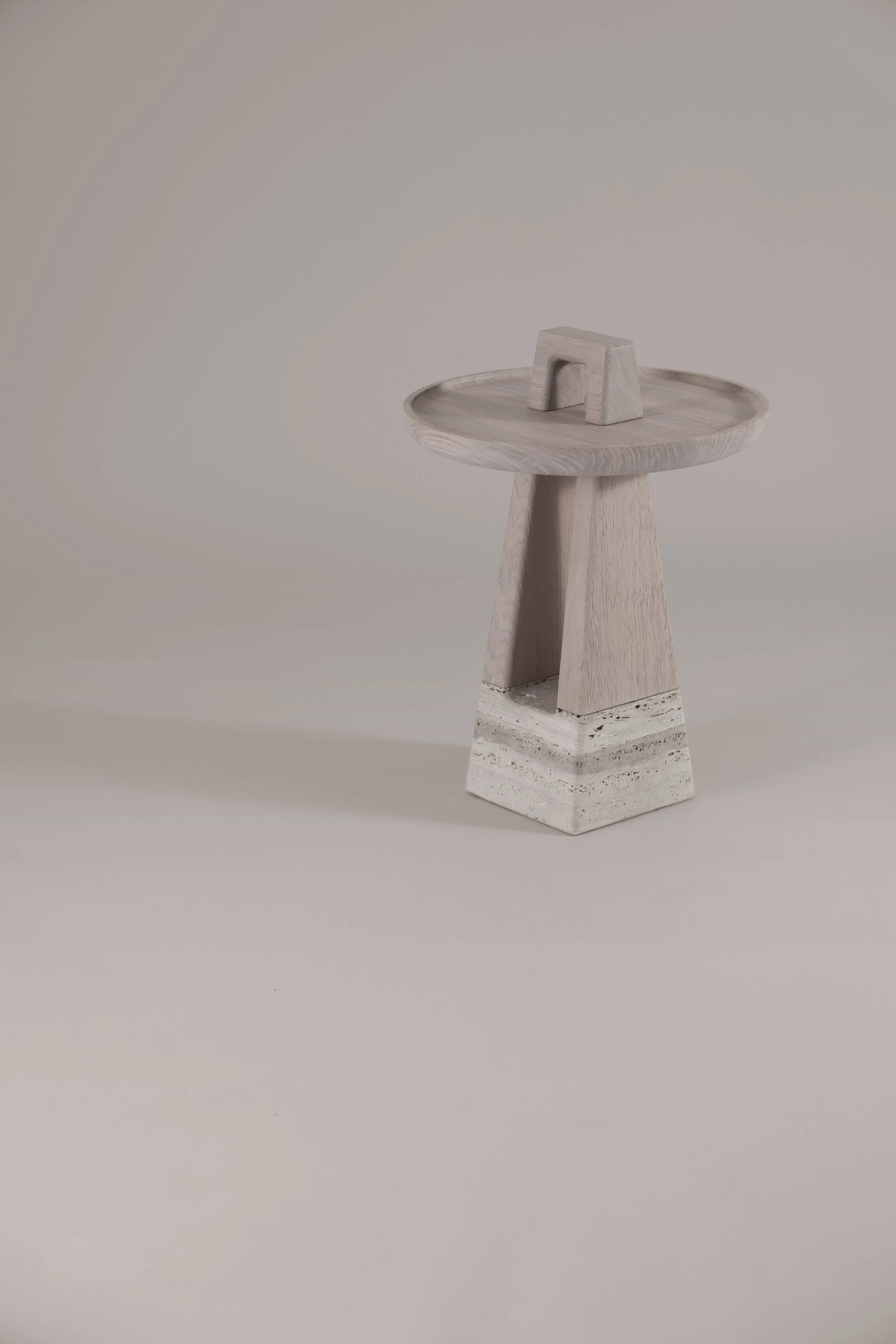 Front view of the Bring Me nomadic side table, featuring a light brushed oak frame resting on a natural Silver Travertine base, handcrafted in Italy.