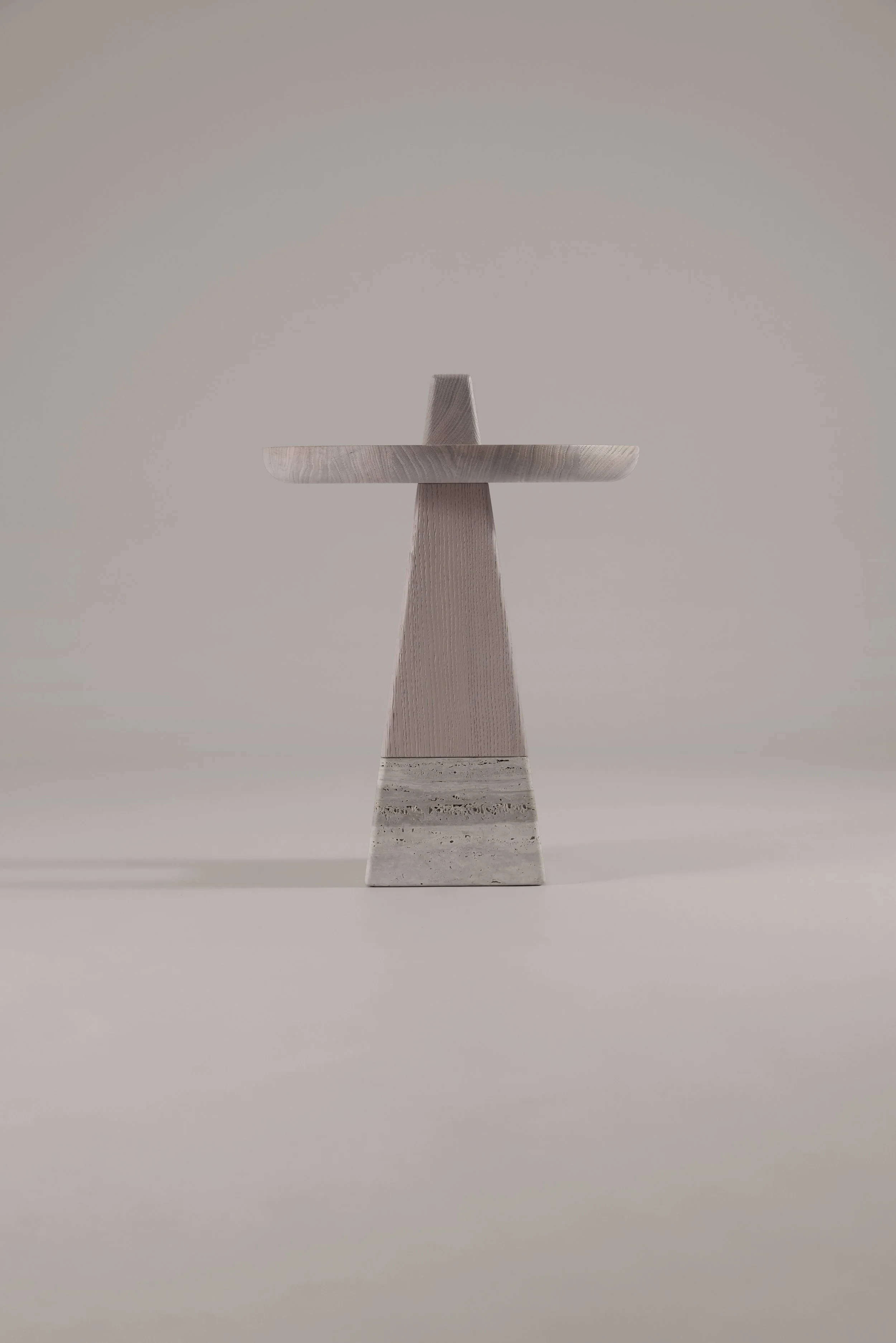 Rear view of the sculptural Bring Me side table, highlighting the open wooden base detail and the contrast with the solid stone foundation.