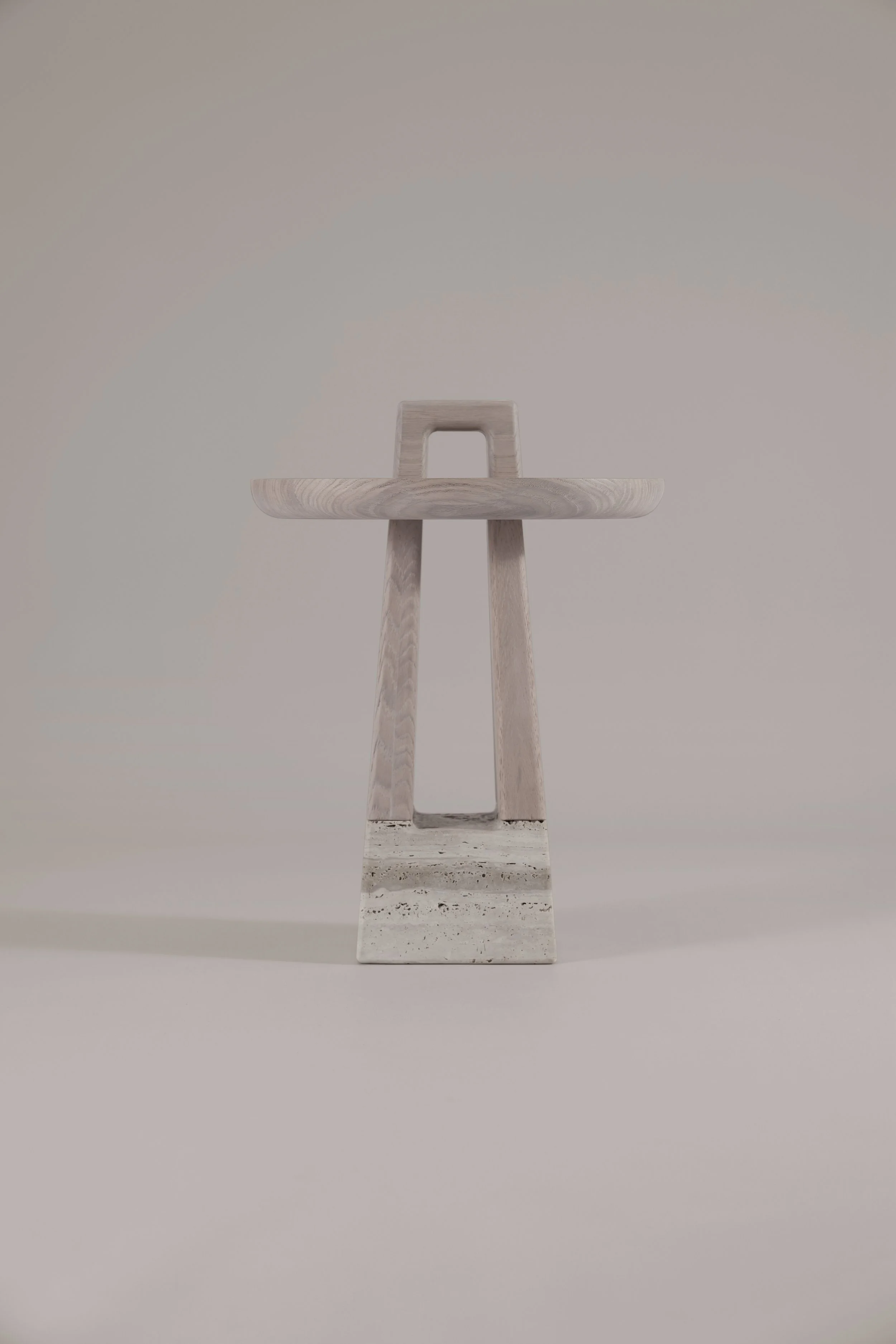 Front view of the Bring Me nomadic side table, featuring a light brushed oak frame resting on a natural Silver Travertine base, handcrafted in Italy.