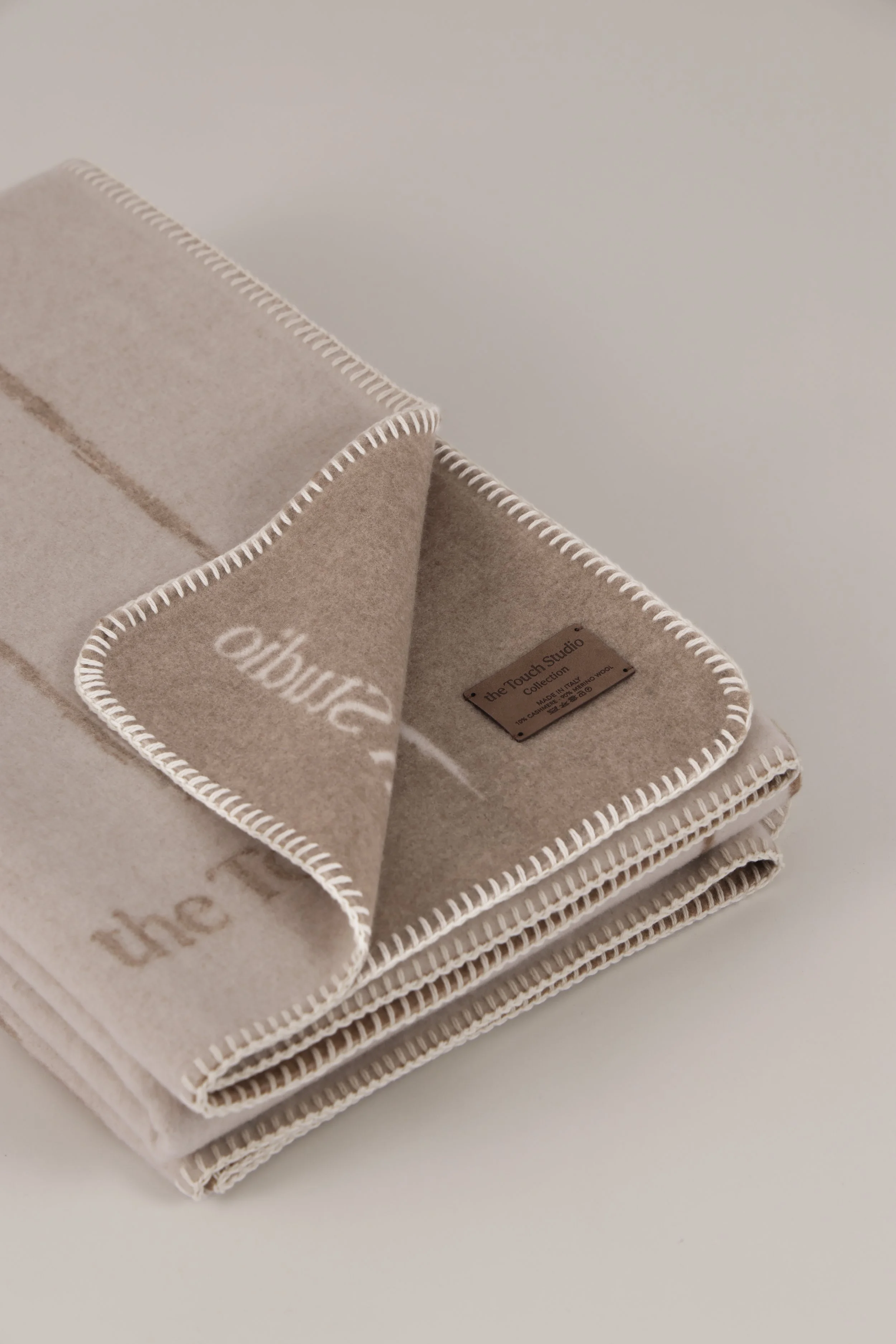 High-end wool cashmere throw with traditional whipstitch edge finish and leather brand label.