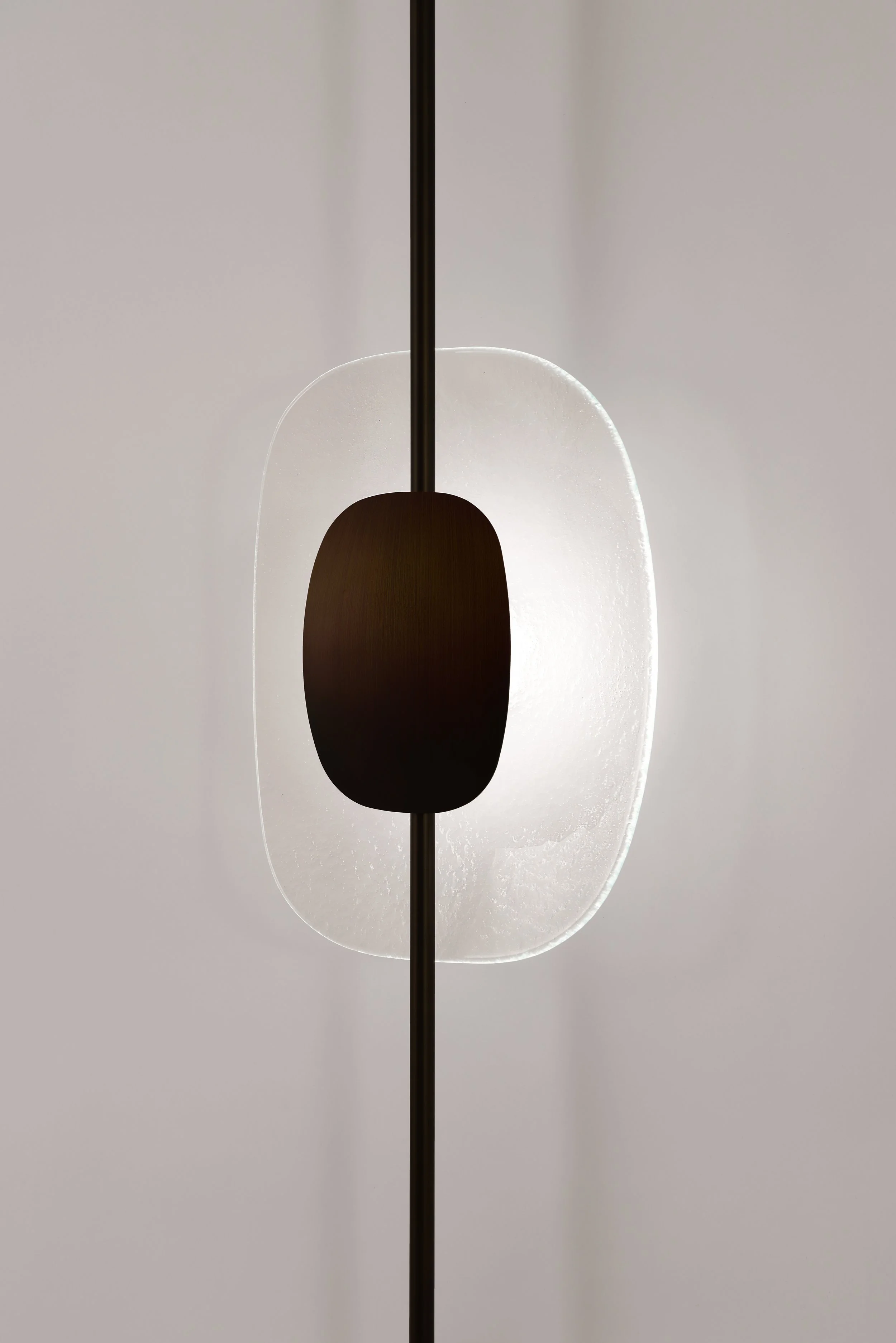Side profile of the Drop Light II wall lamp. Detail of the minimalist curved black metal stem and the flush-to-wall mounting system for a clean architectural integration.