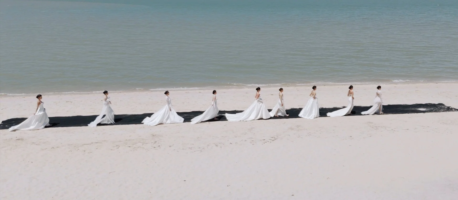23 Wedding Luxe First Coastal fashion show white gowns walking on beach