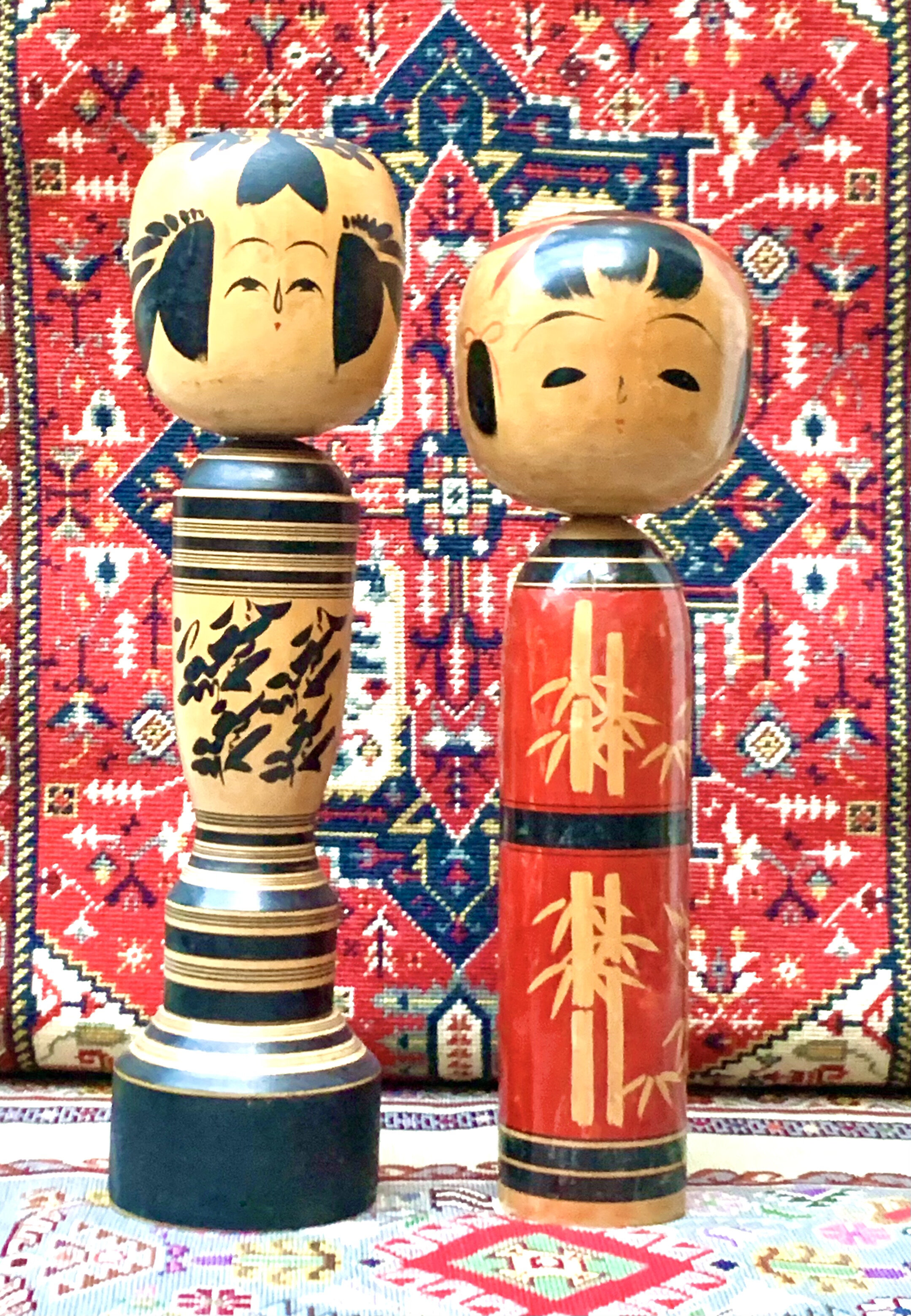 A pair of Japanese 1950-60's Kokeshi Dolls, wooden, handpainted, artist signed. Kokeshi, a traditional Japanese children's toy. These are unusual for their size, Black 50 cm in Height, Red 46 cm. Price on Application