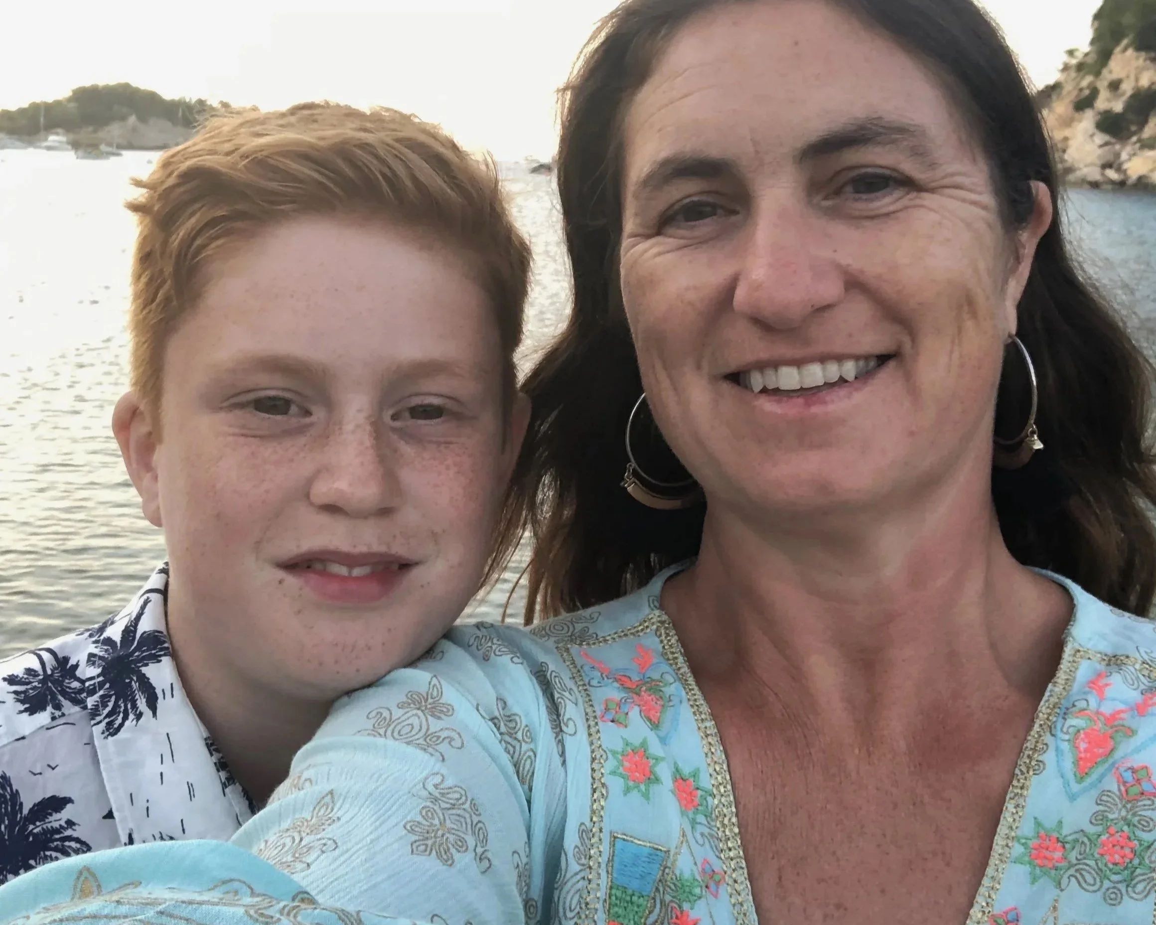 “Mother and son smiling at the beach at sunset, outdoor family moment near the water.”