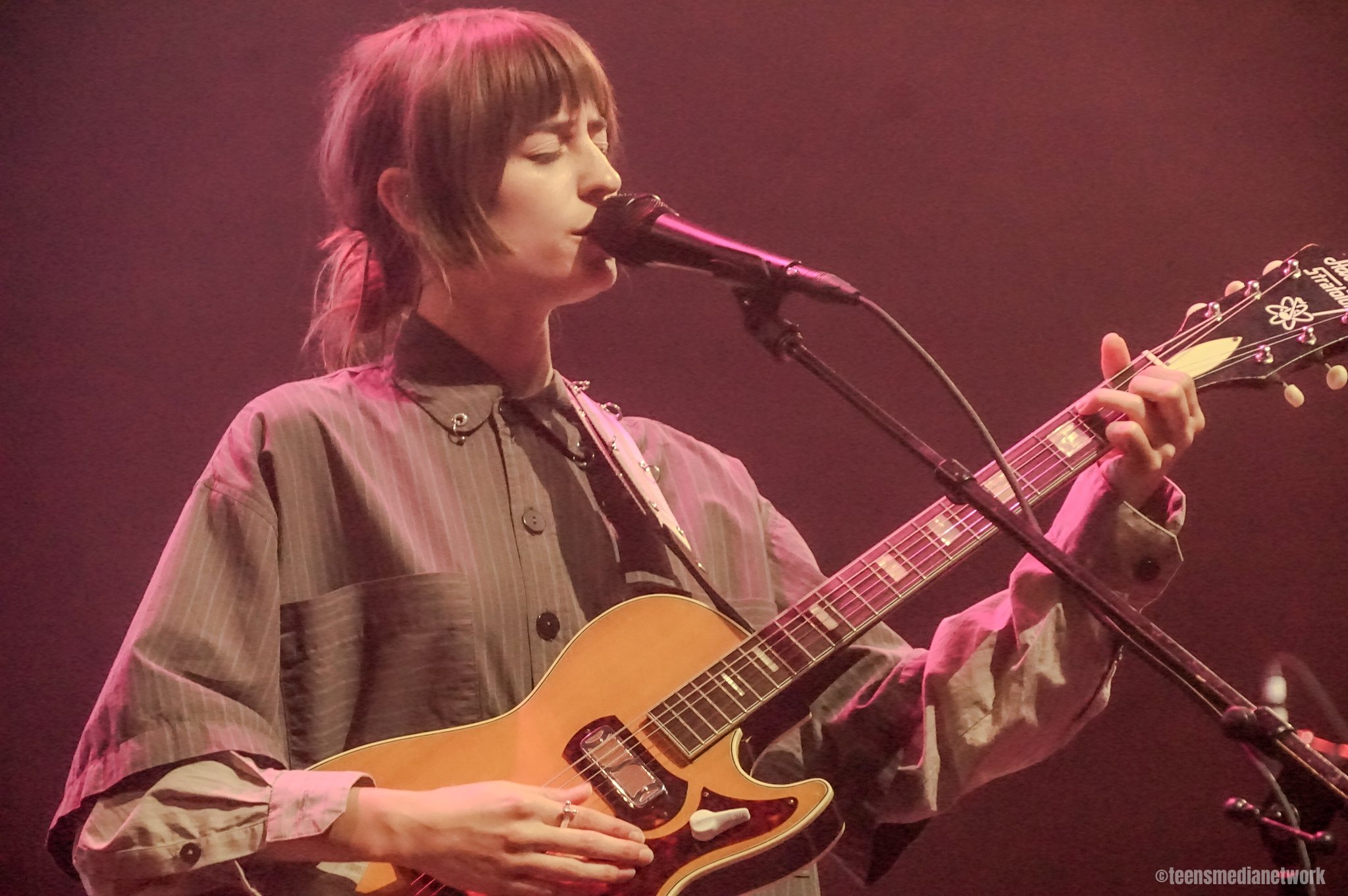 A musician performing on stage with a guitar and microphone.
