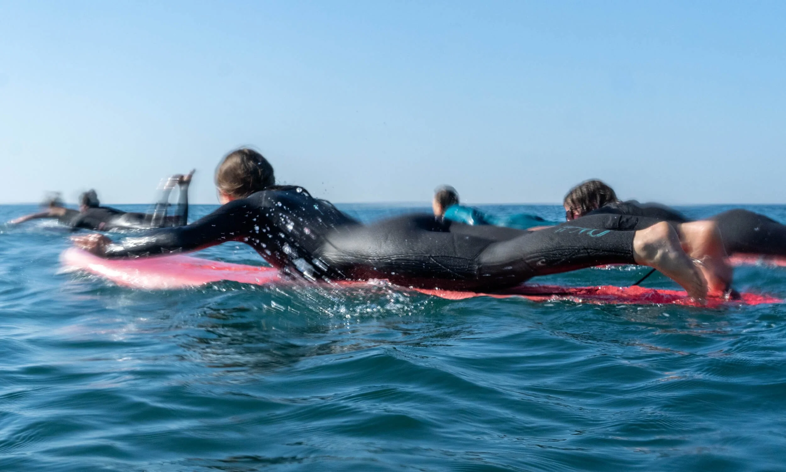 Group-of-surfers-padding-on-surfboards-at-Brighton-beach.jpg