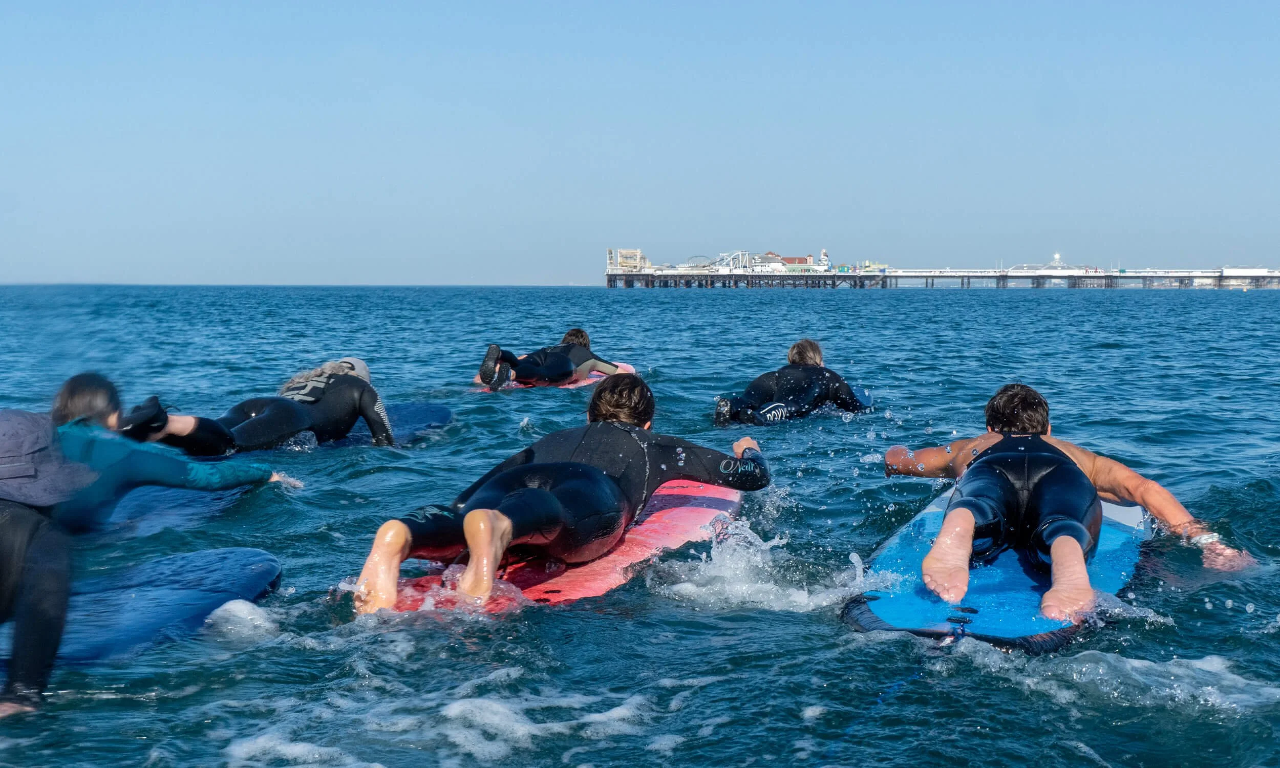 Group-of-surfers-padding-training-on-surfboards-at-Brighton-beach.jpg