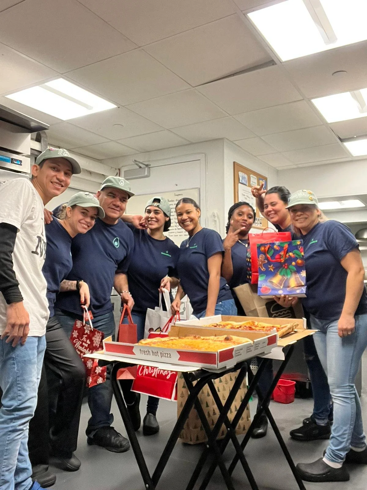 Group of people celebrating Christmas with pizza and gifts in an office break room