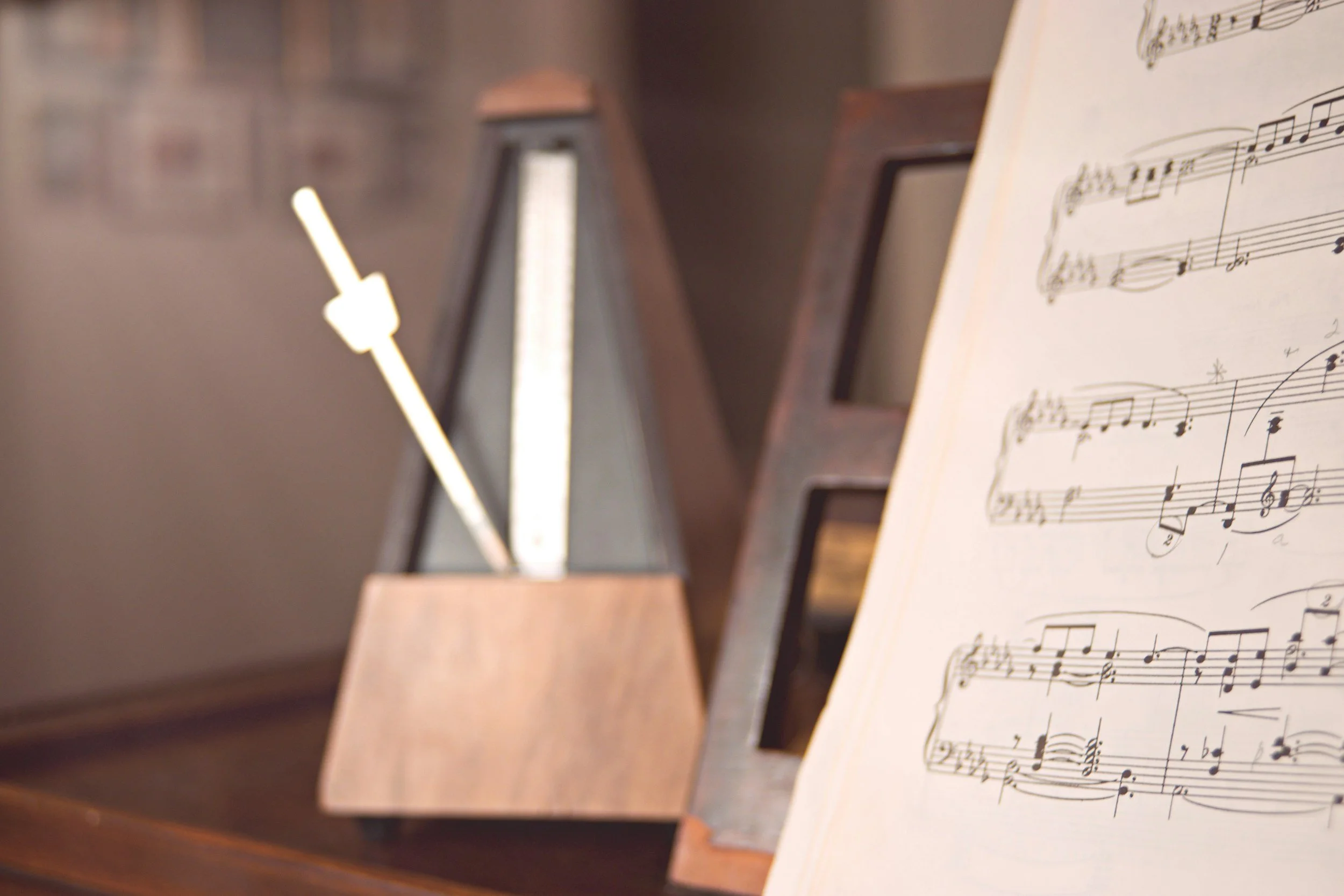 Sheet music on a stand with a metronome in the background.
