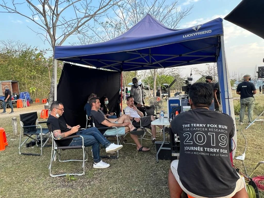People sitting under a blue canopy with equipment and cameras at an outdoor event, promoting the Terry Fox Run for cancer research in 2019.