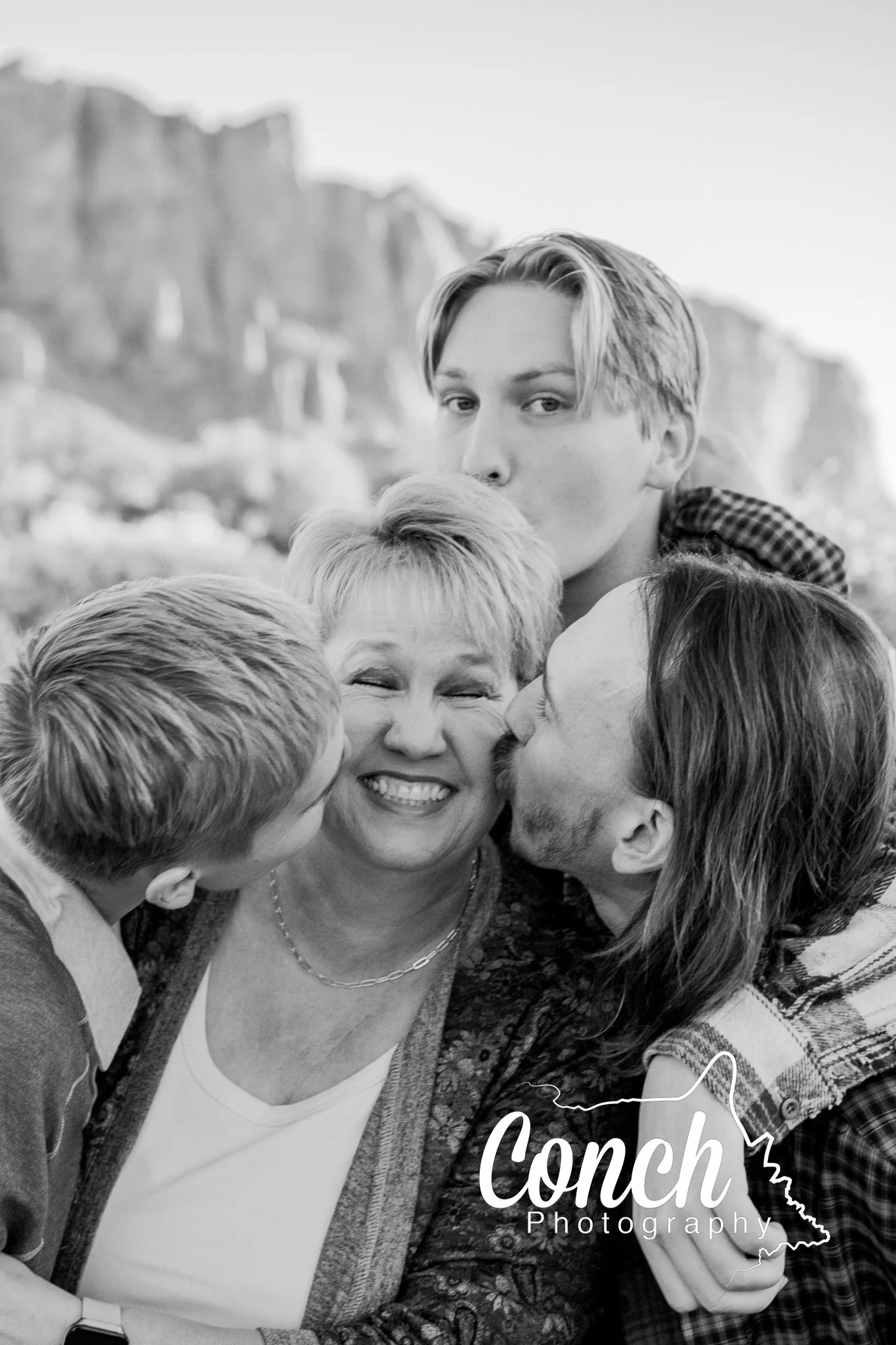 Black and White image of a Mother being kissed by her three sons at First Water Trailhead