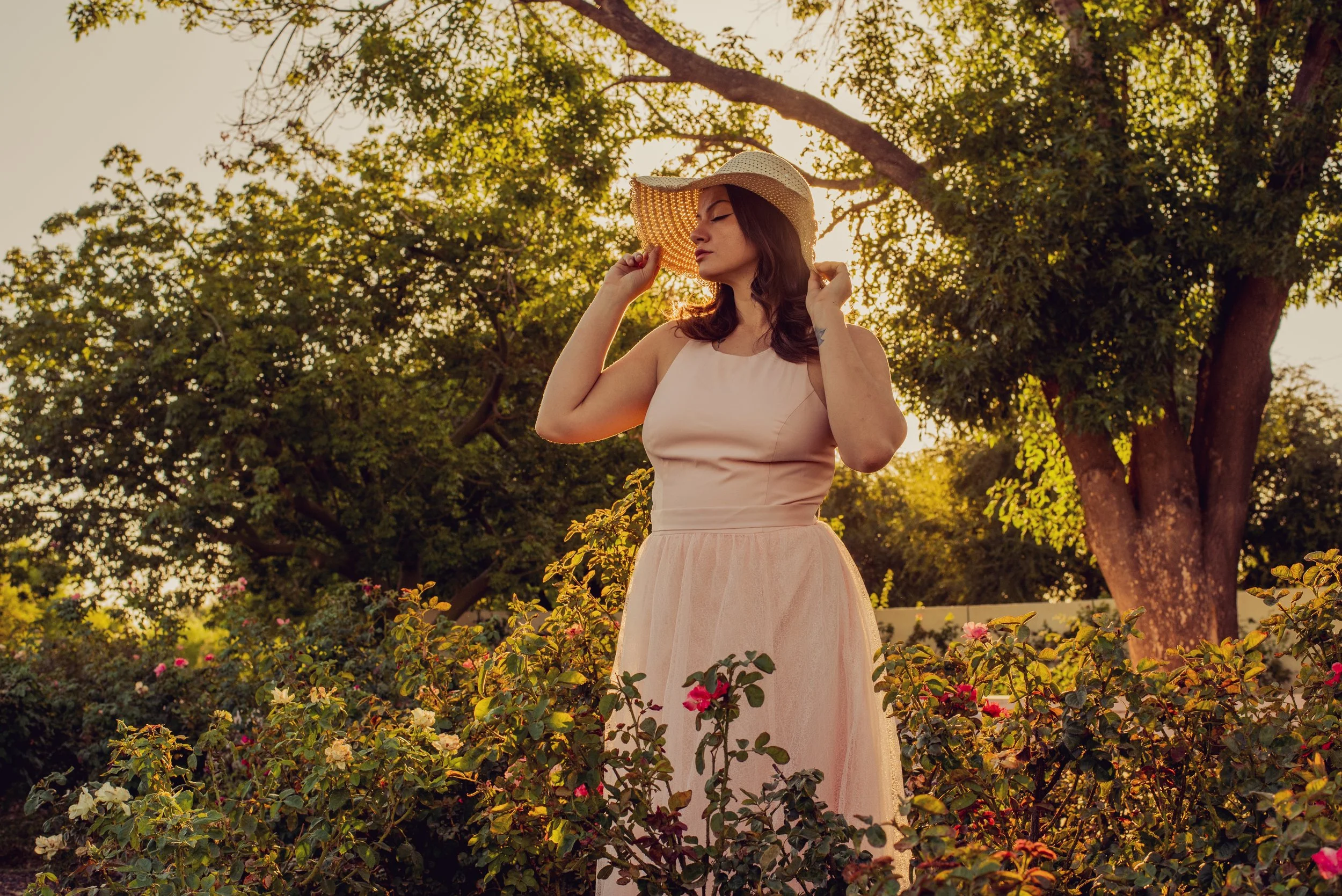 Model stands with sunhat in the MCC Rose Garden at sunset