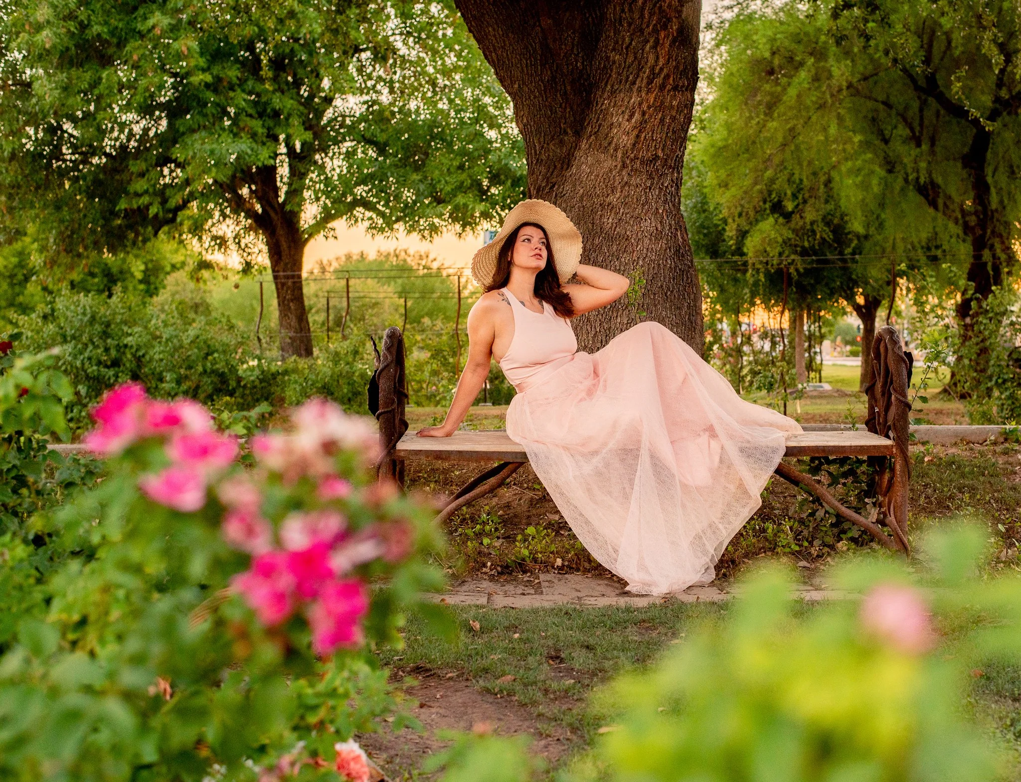 Model sitting with sunhat in the MCC Rose Garden at sunset