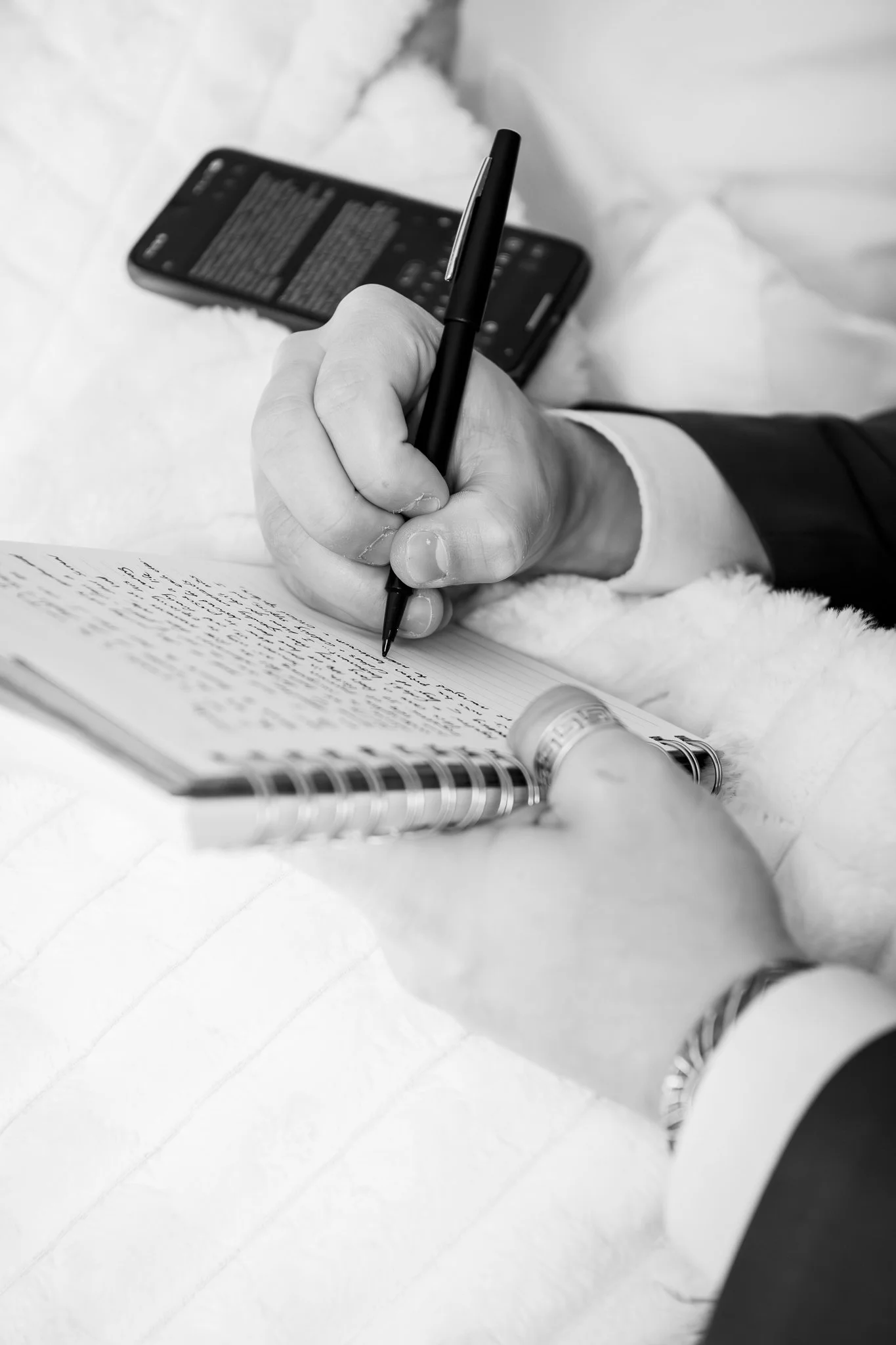 Black and white close up image of the groom writing his vows.
