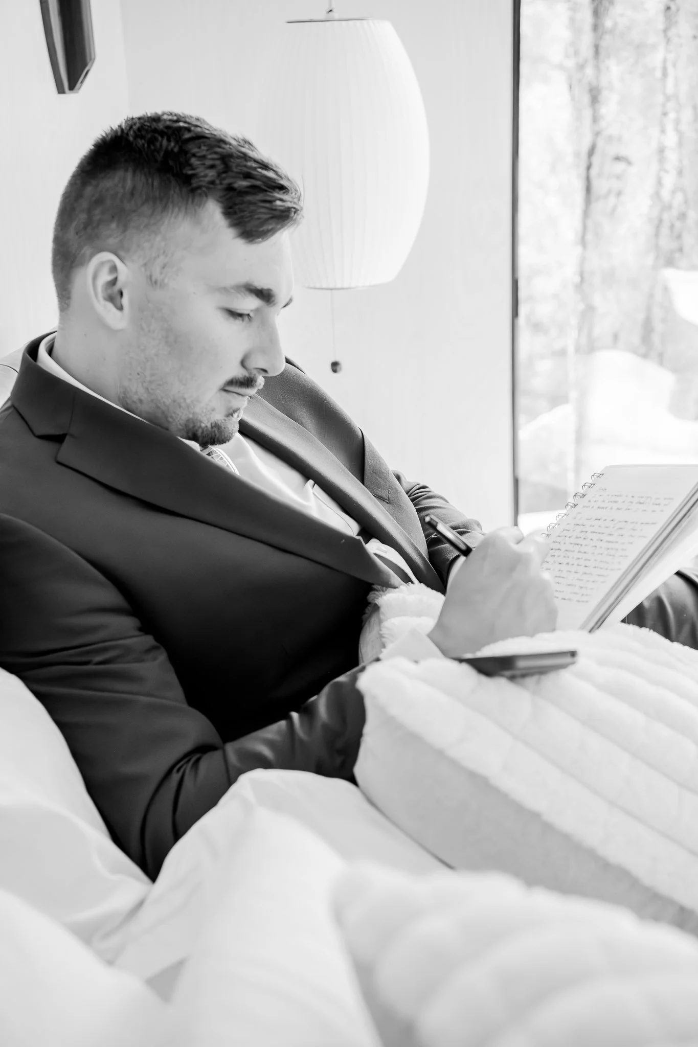 Black and white image of the groom writing down his vows before their destination elopement