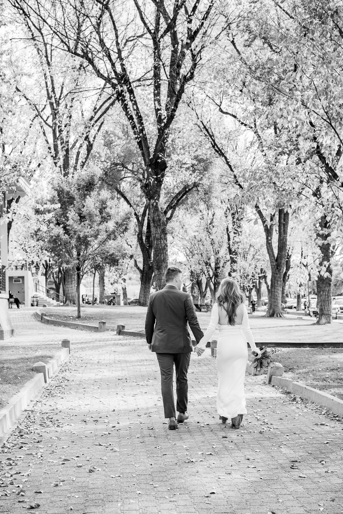 Black and white image of bride and groom walking hand-in-hand in Downtown Prescott, Arizona