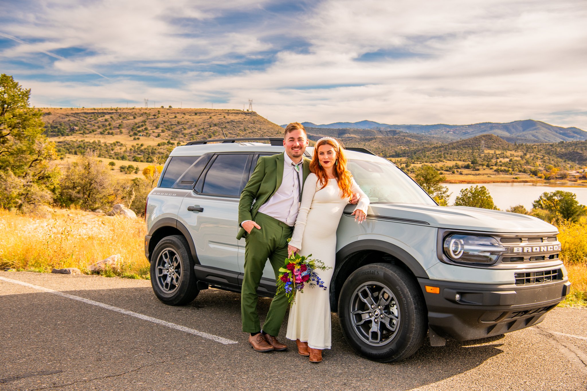 Bride and groom stand against their rented Ford Bronco during their destination adventure elopement at Watson Lake in Prescott, Arizona.