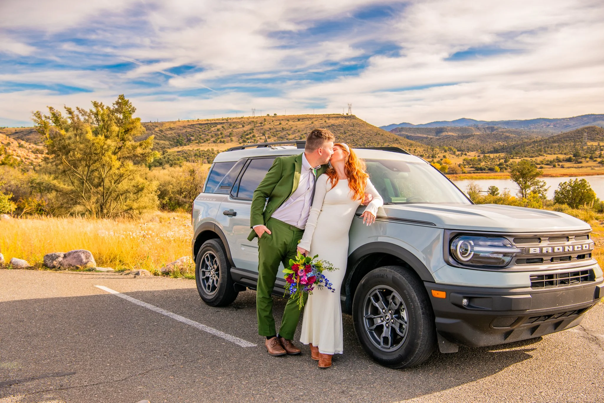 Bride and groom kiss while leaning on their rented Bronco at Watson Lake in Prescott, Arizona during their Destination Adventure Elopement.