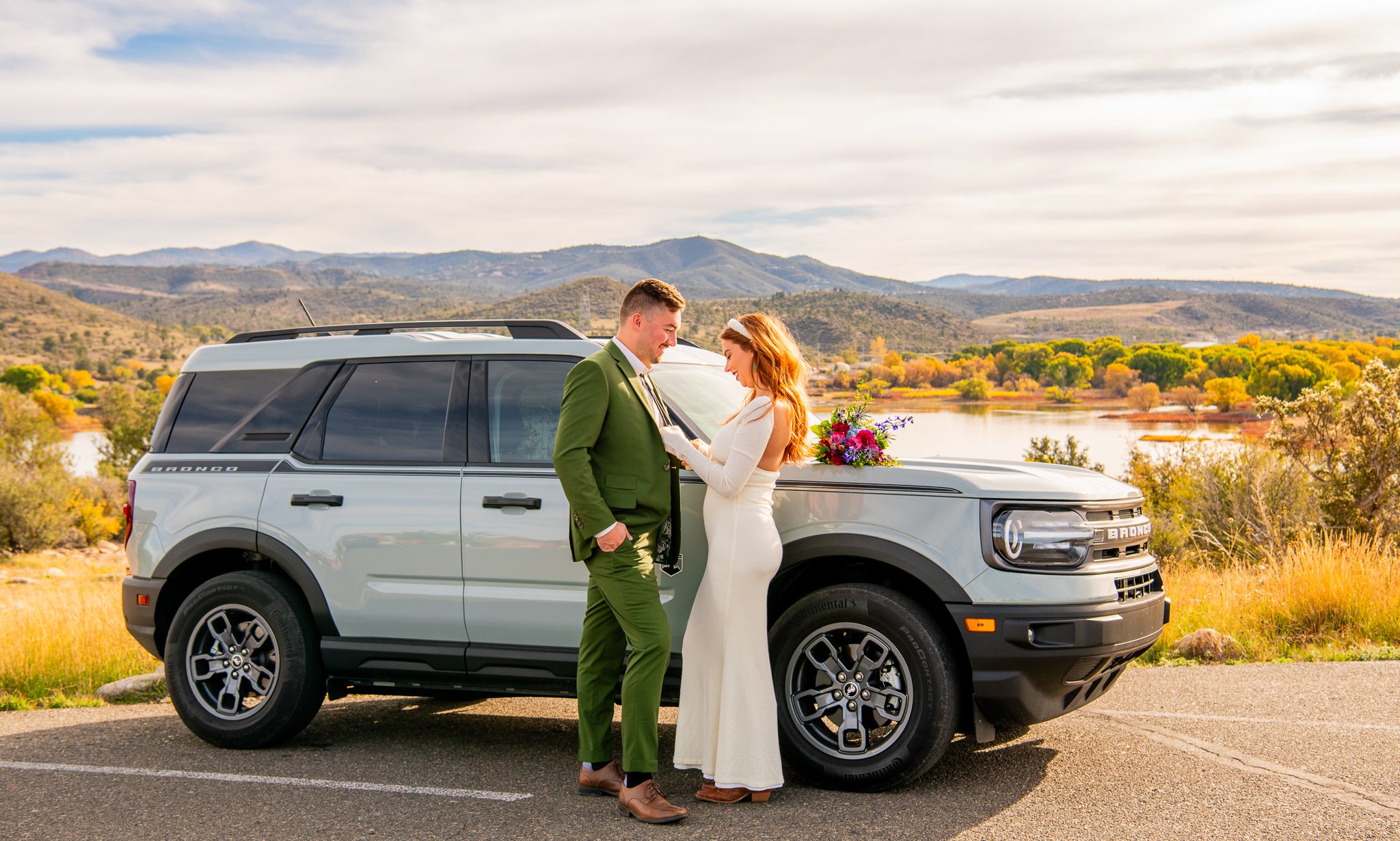 Bride fixing groom's tie in front of their rented Ford Bronco at Watson Lake in Prescott, Arizona during their destination adventure elopement.