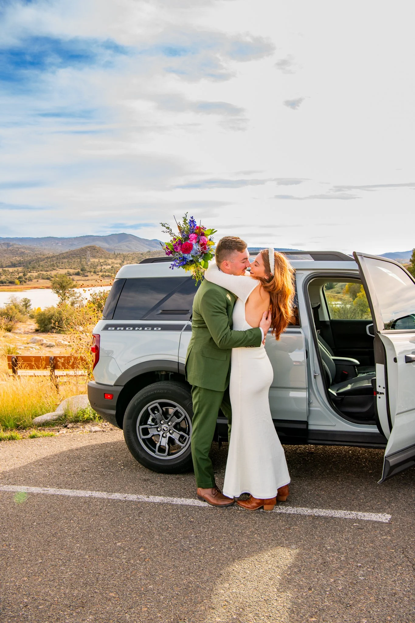 Bride and groom hold each other close in front of their Ford Bronco at Watson Lake in Prescott, Arizona during their destination adventure elopement.