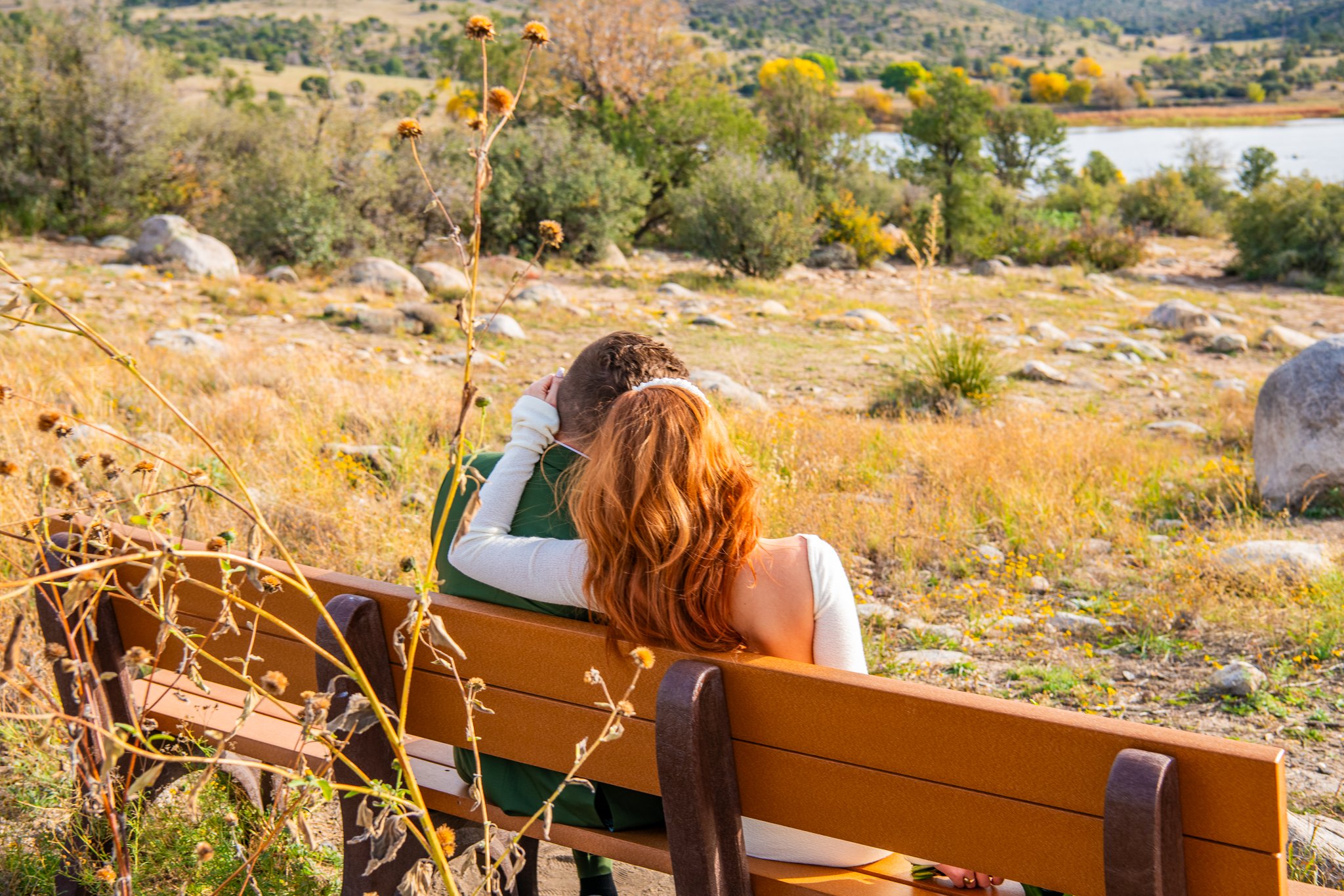 Sentimental image of the backside of the bride and groom sitting each other on a bench at Watson Lake in Prescott, Arizona during their destination adventure elopement.