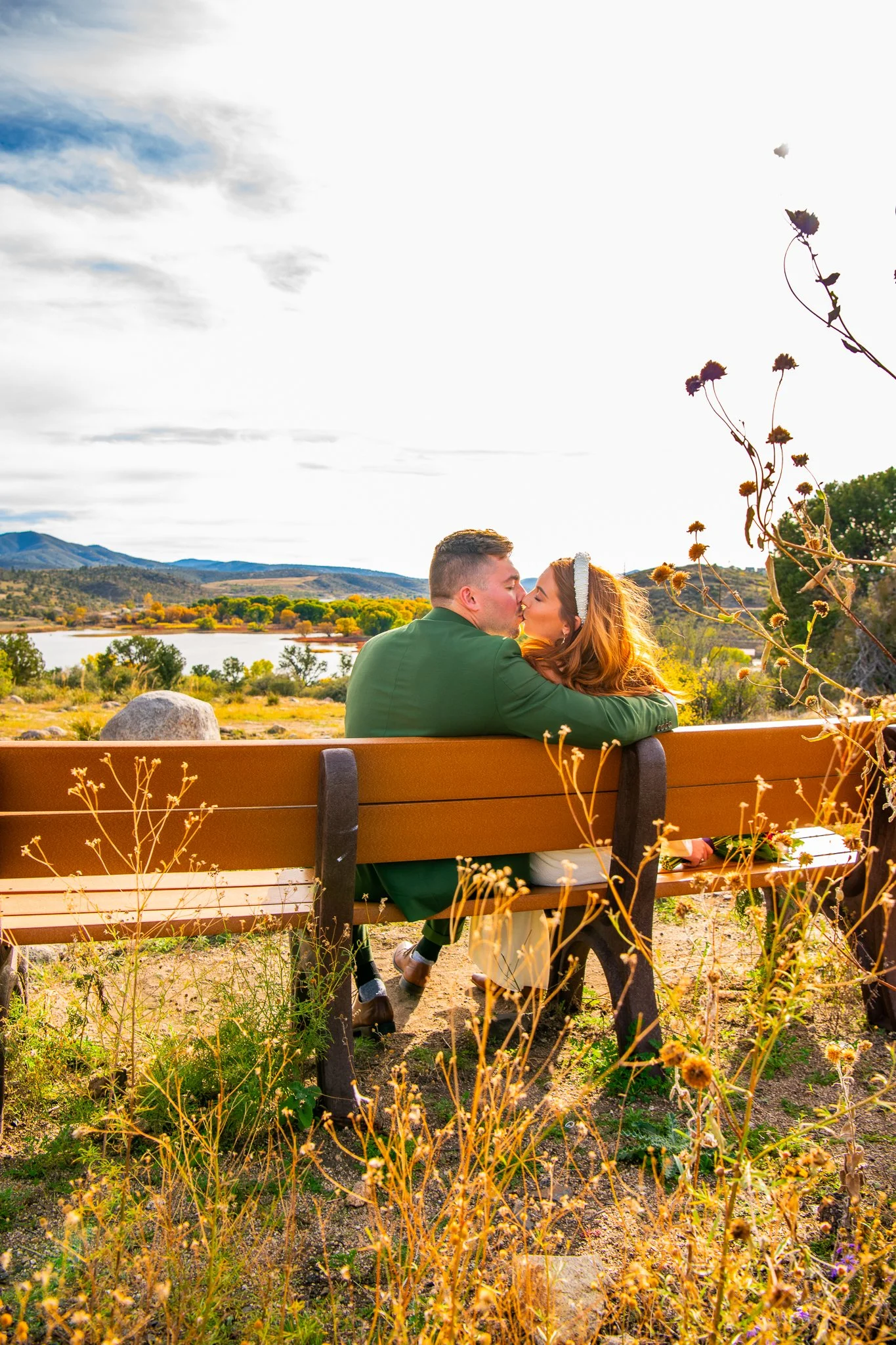 Bride and Groom kissing on a bench amongst the unique desert of Watson Lake in Prescott, Arizona during their destination adventure elopement.