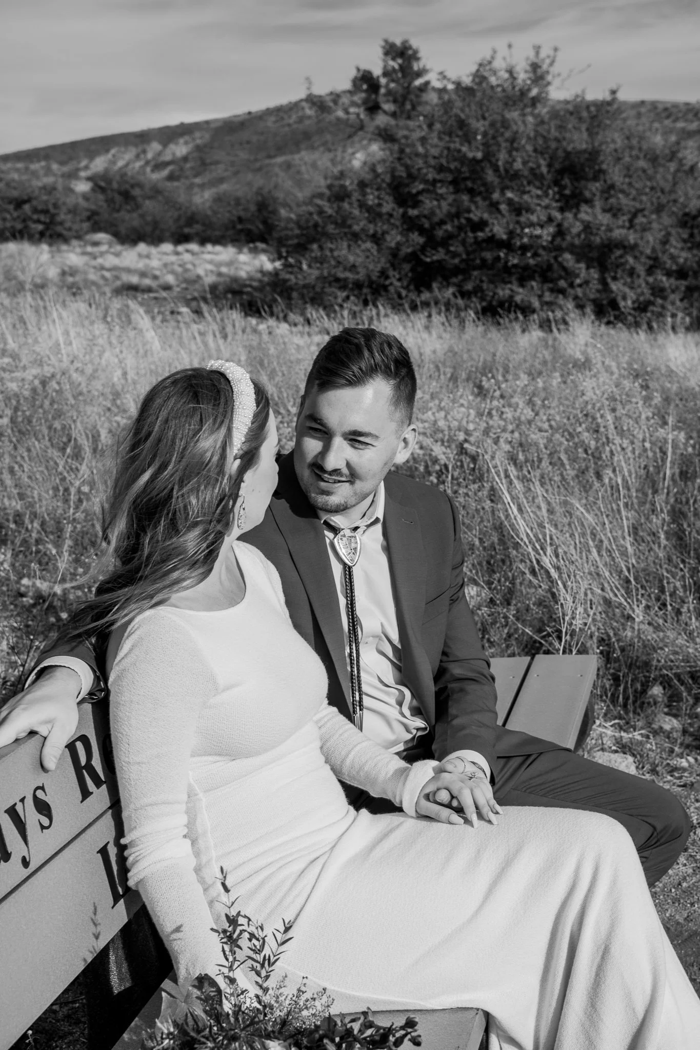 Black and white image of the bride and groom sitting together and conversing at Watson Lake in Prescott, Arizona.