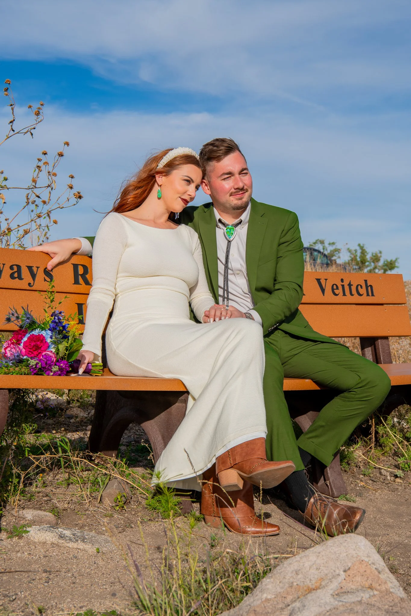 Full sun image of bride leaning on groom while sitting on a bench at Watson Lake in Prescott, Arizona during their destination adventure elopement.