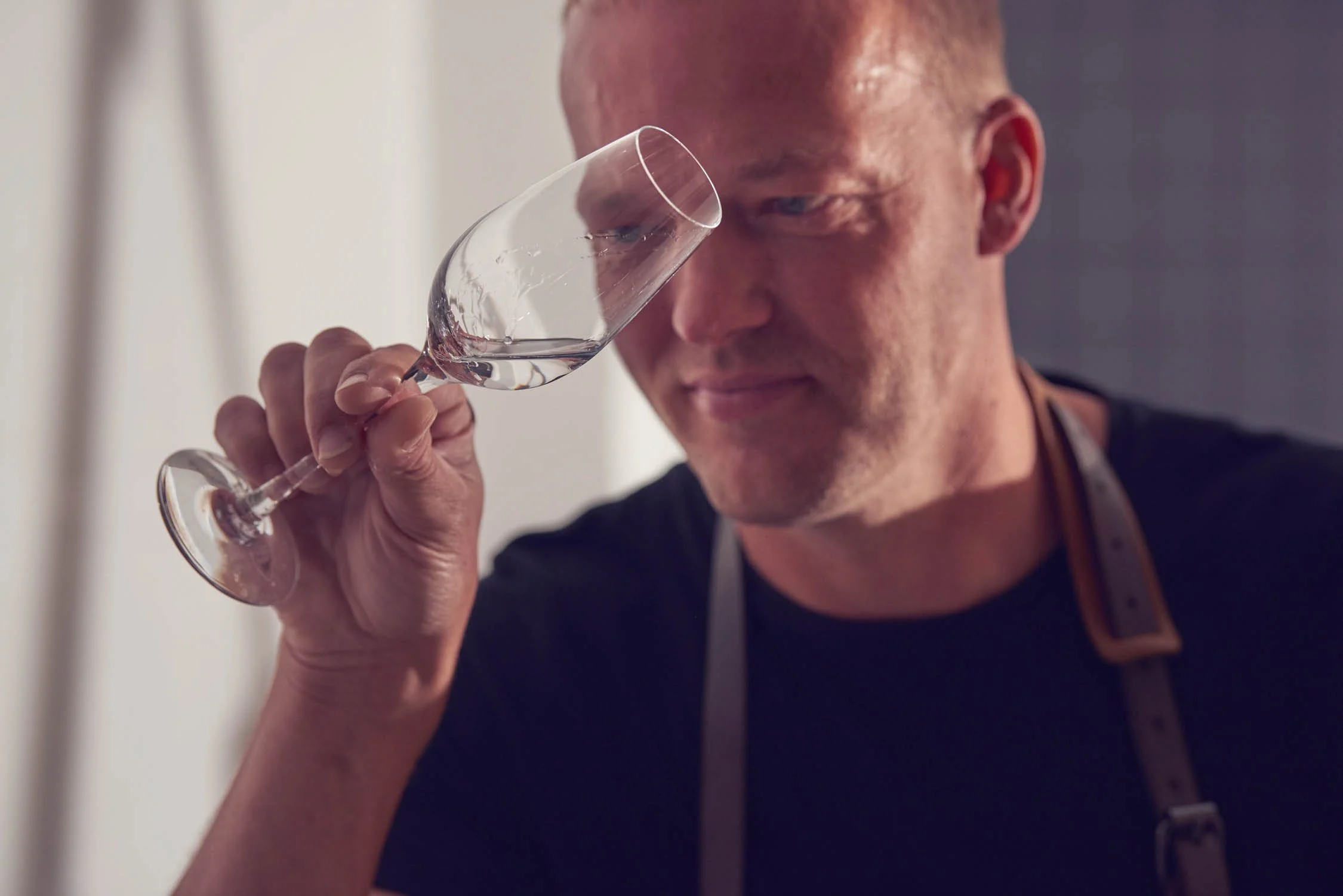 A man is smelling a glass of white wine