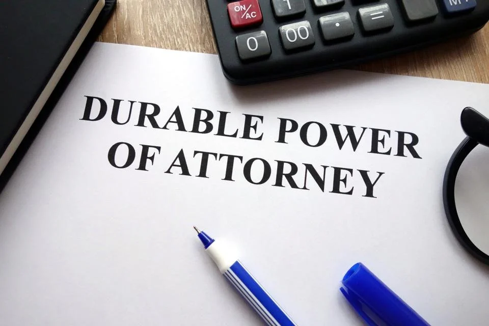 Durable power of attorney typed in bold font on paper, pen, glasses and calculator on desk