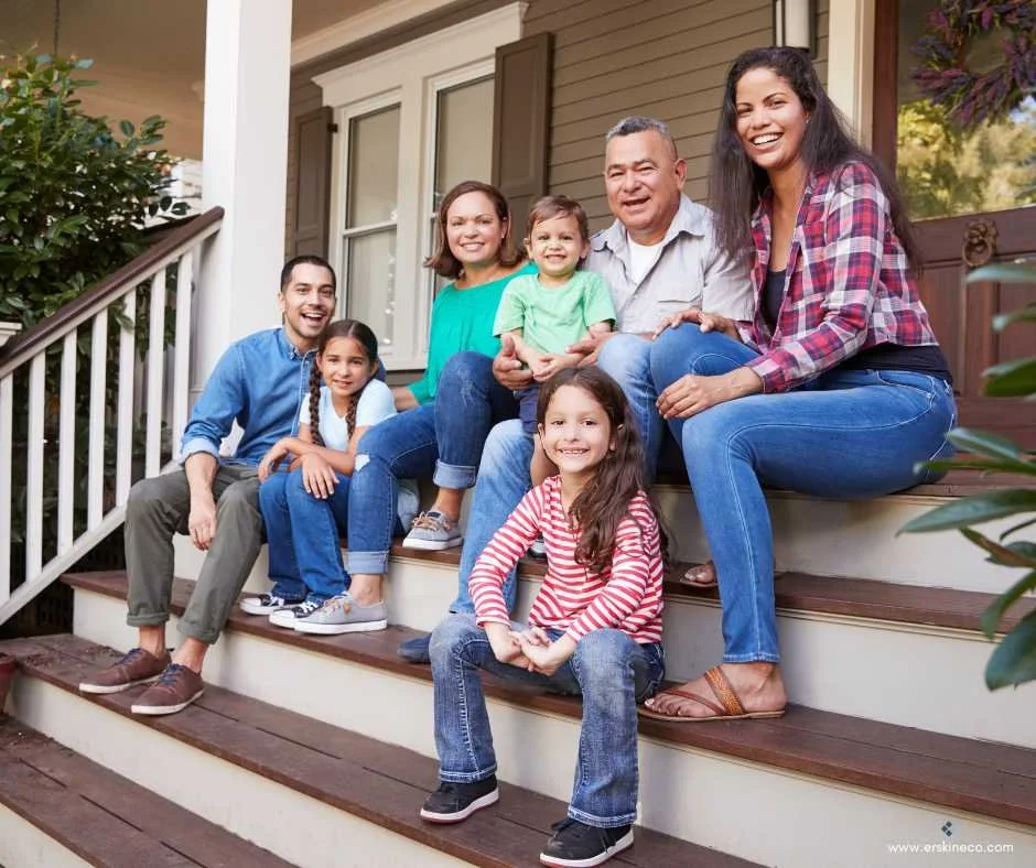 Multi-generational family sitting on the steps leading up to a porch and front door to a house
