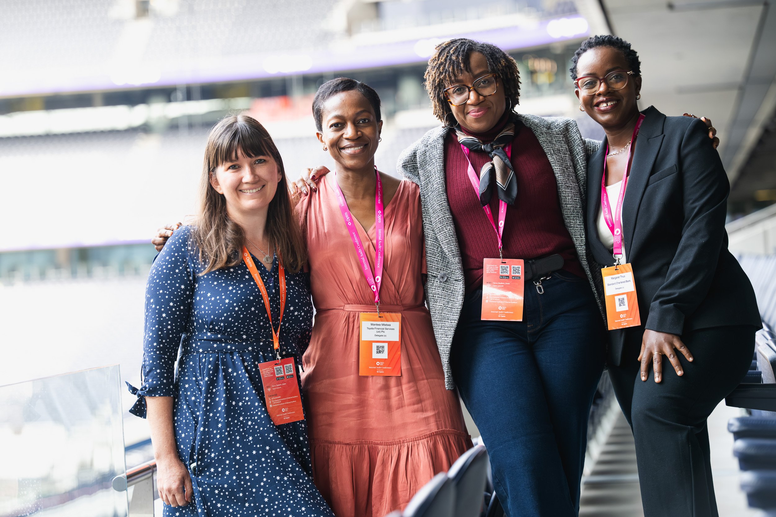 Four conference delegates standing together inside Tottenham Hotspur Stadium.