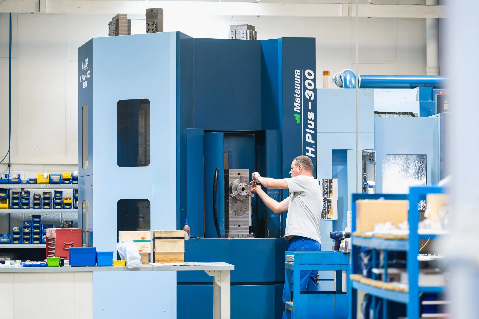 Team member working beside a large blue machine at WLR Precision Engineering.