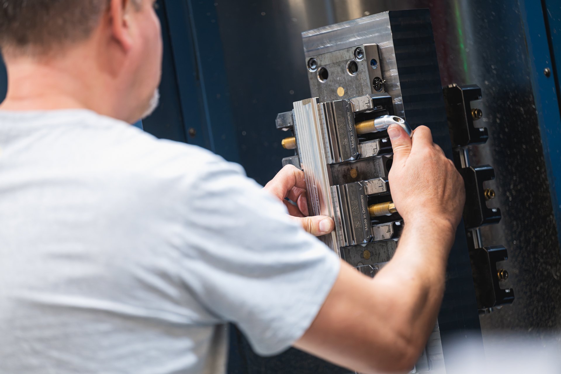 Close view of a team member’s hands working on a metal fixture inside a machine.