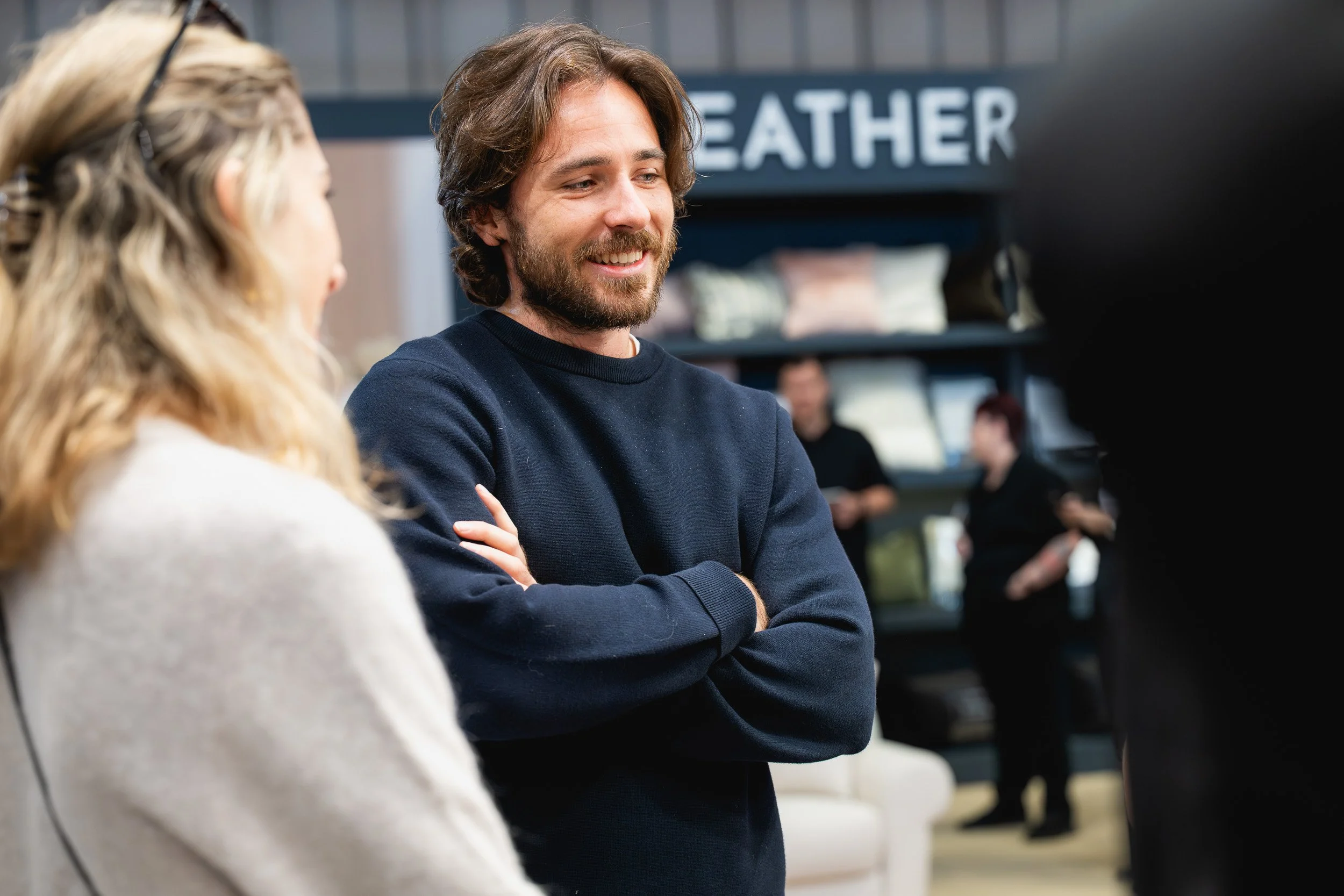 A smiling man talking with visitors beside a stand at Grand Designs Live.