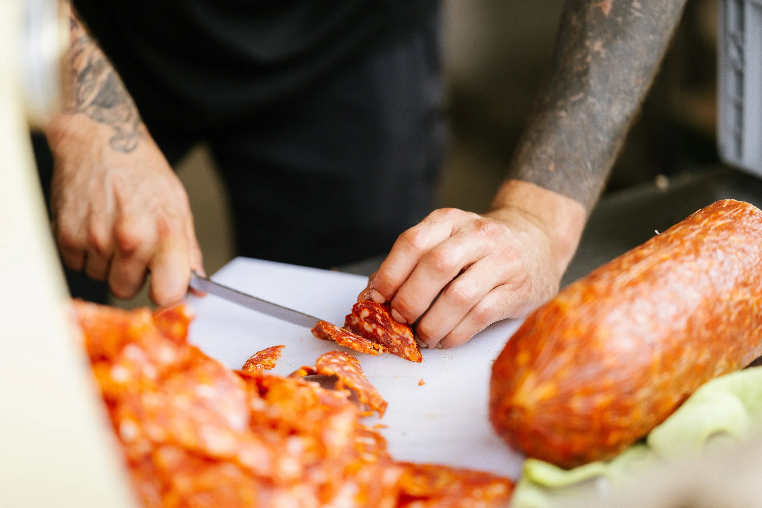 Close-up of hands slicing ingredients during food preparation.