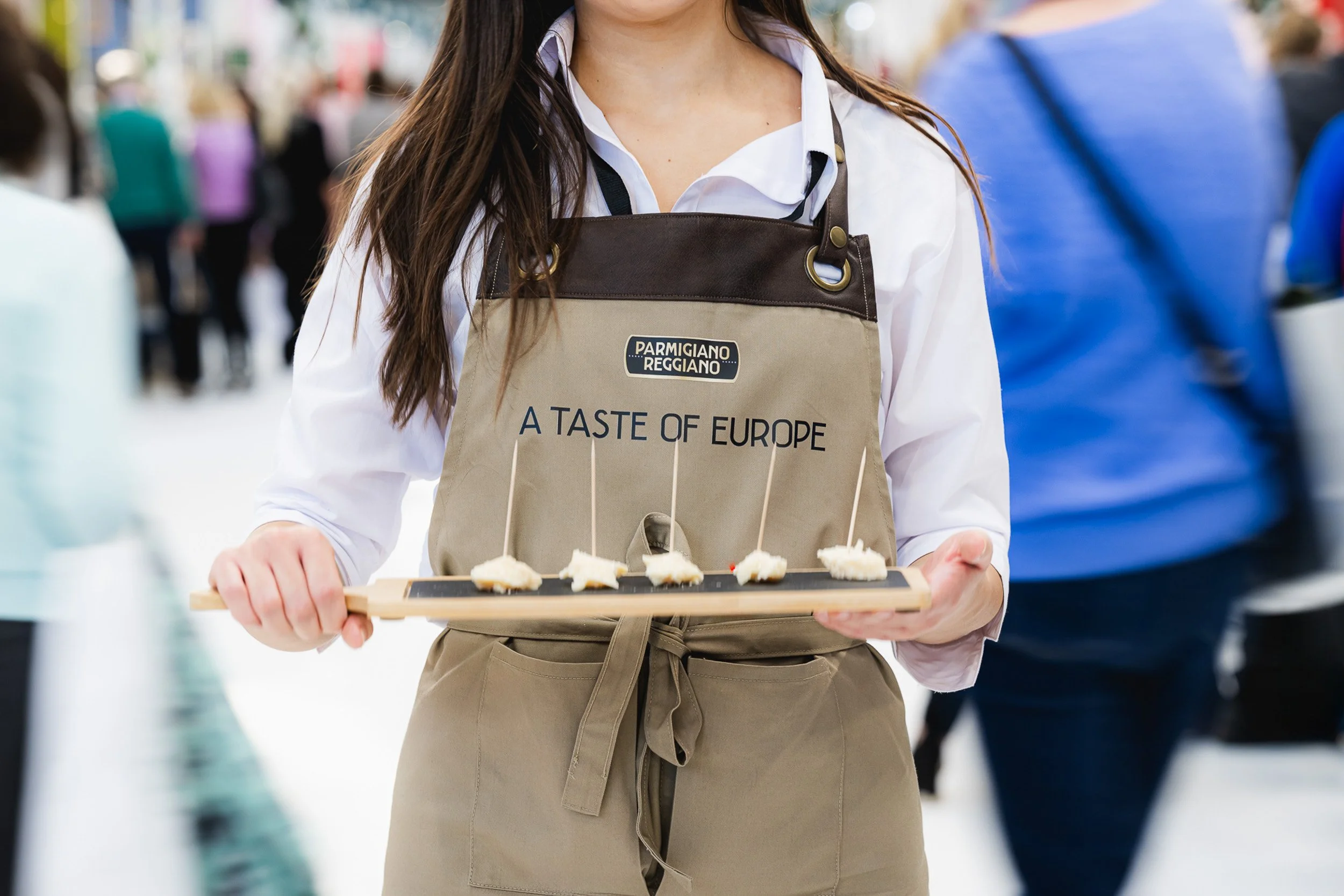 An exhibition team member carrying a tray of food samples.